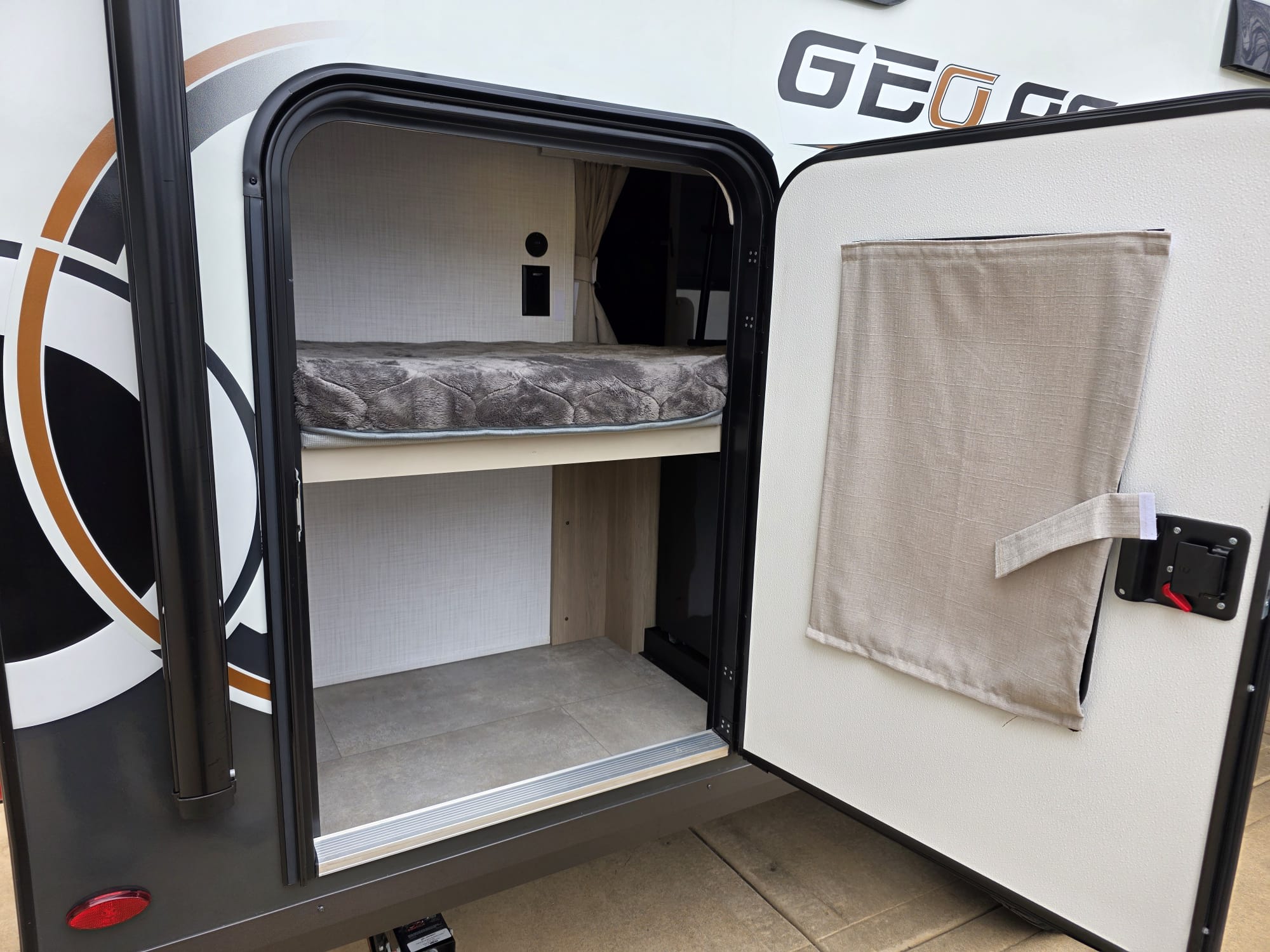 RV rental: Open exterior hatch shows bunk bed and floor storage. Perfect for camping adventures.. Forest River Rockwood Geo Pro 2025