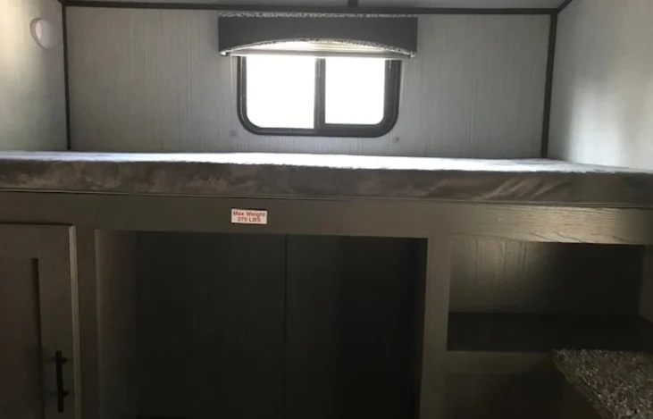This RV rental features a cozy bunk bed with a window, built-in storage, and a clearly marked 275 lb weight limit.. Cruiser RV MPG Ultra Lite 2021