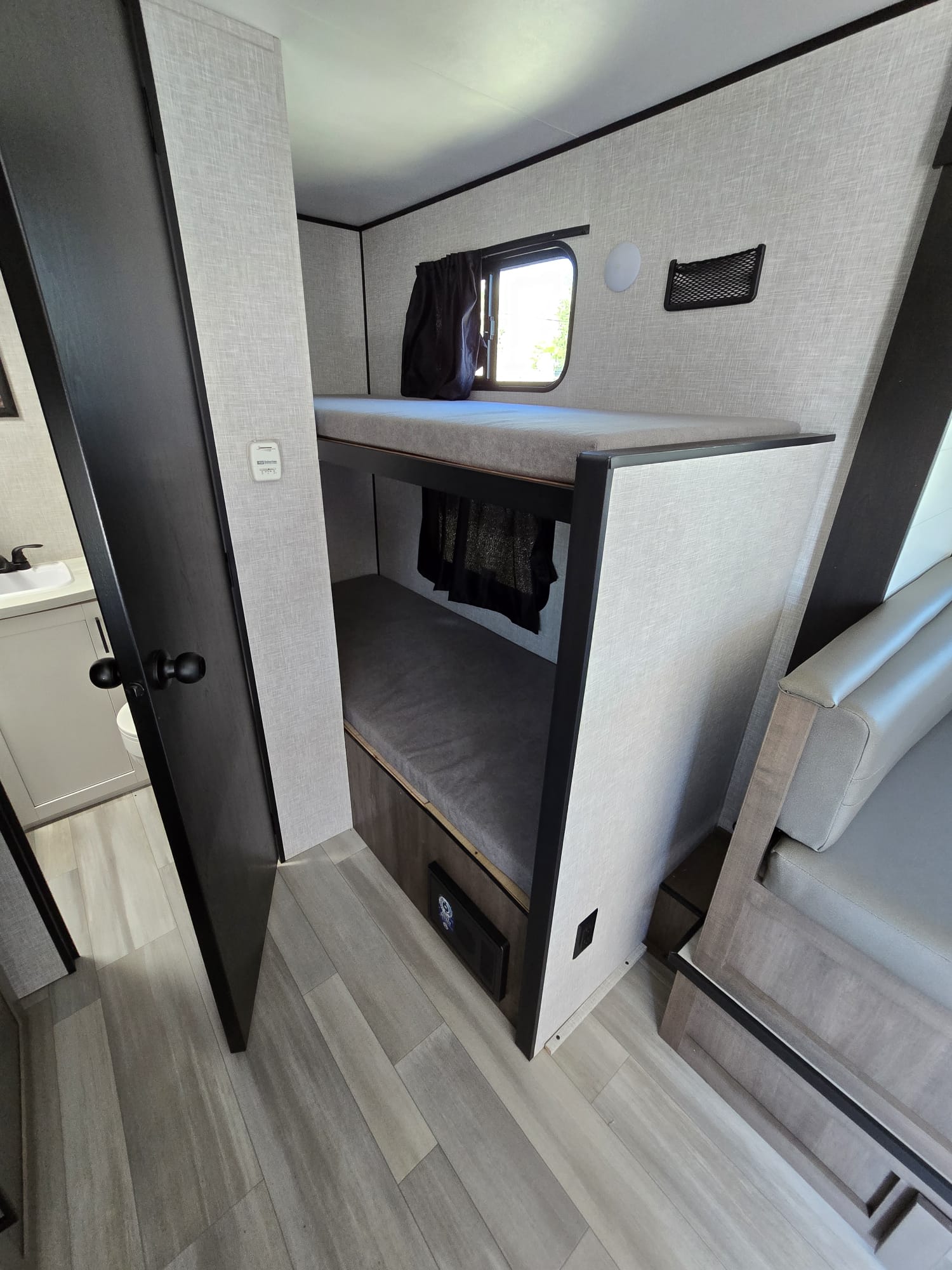 Cozy RV rental interior with bunk beds, adjacent bathroom, and seating area, perfect for family travel.. Starcraft Autumn Ridge 2025