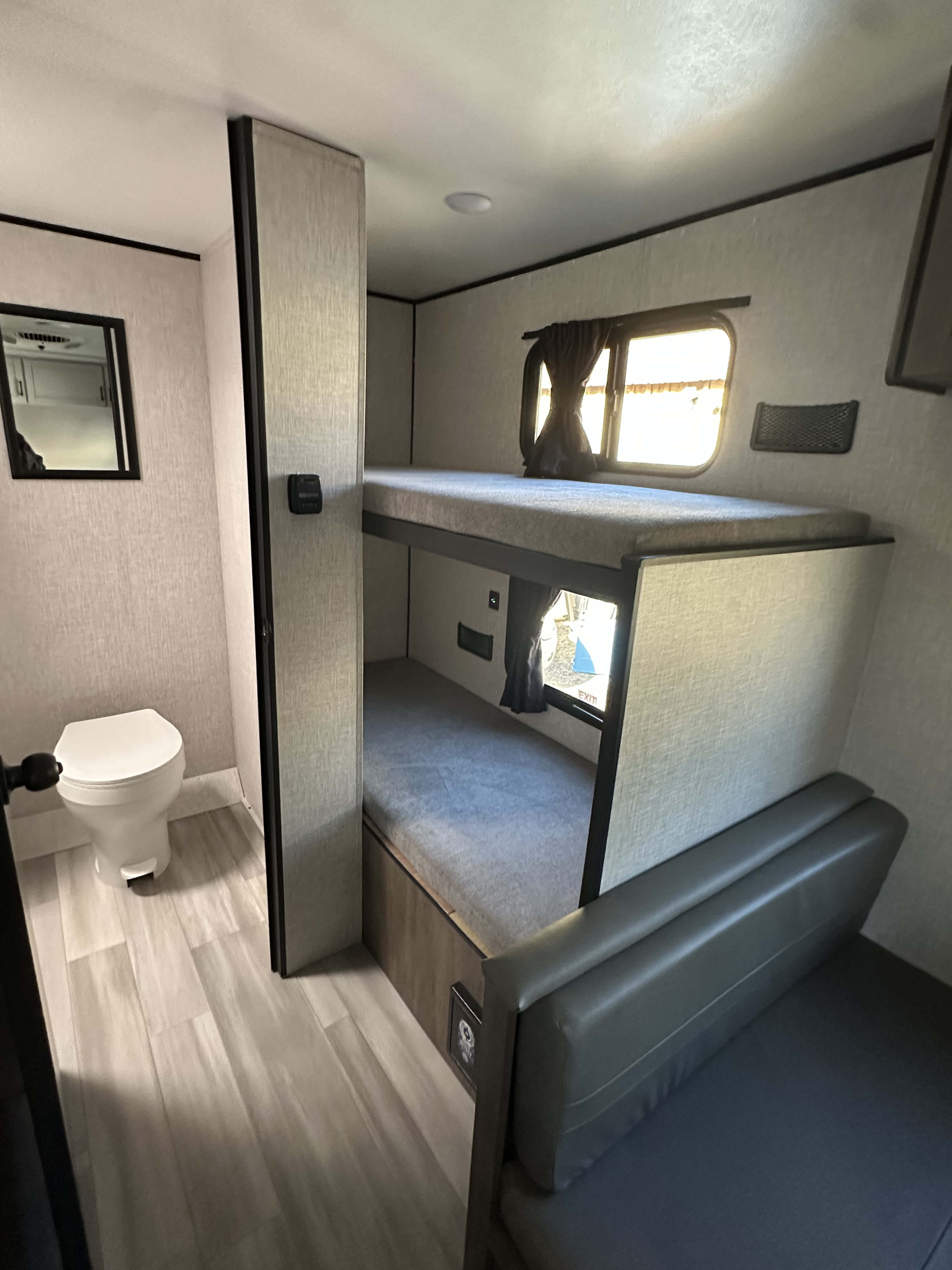 Cozy rv rental interior with bunk beds, a compact toilet, and a padded seating bench for efficient space use.. Starcraft Autumn Ridge 2025