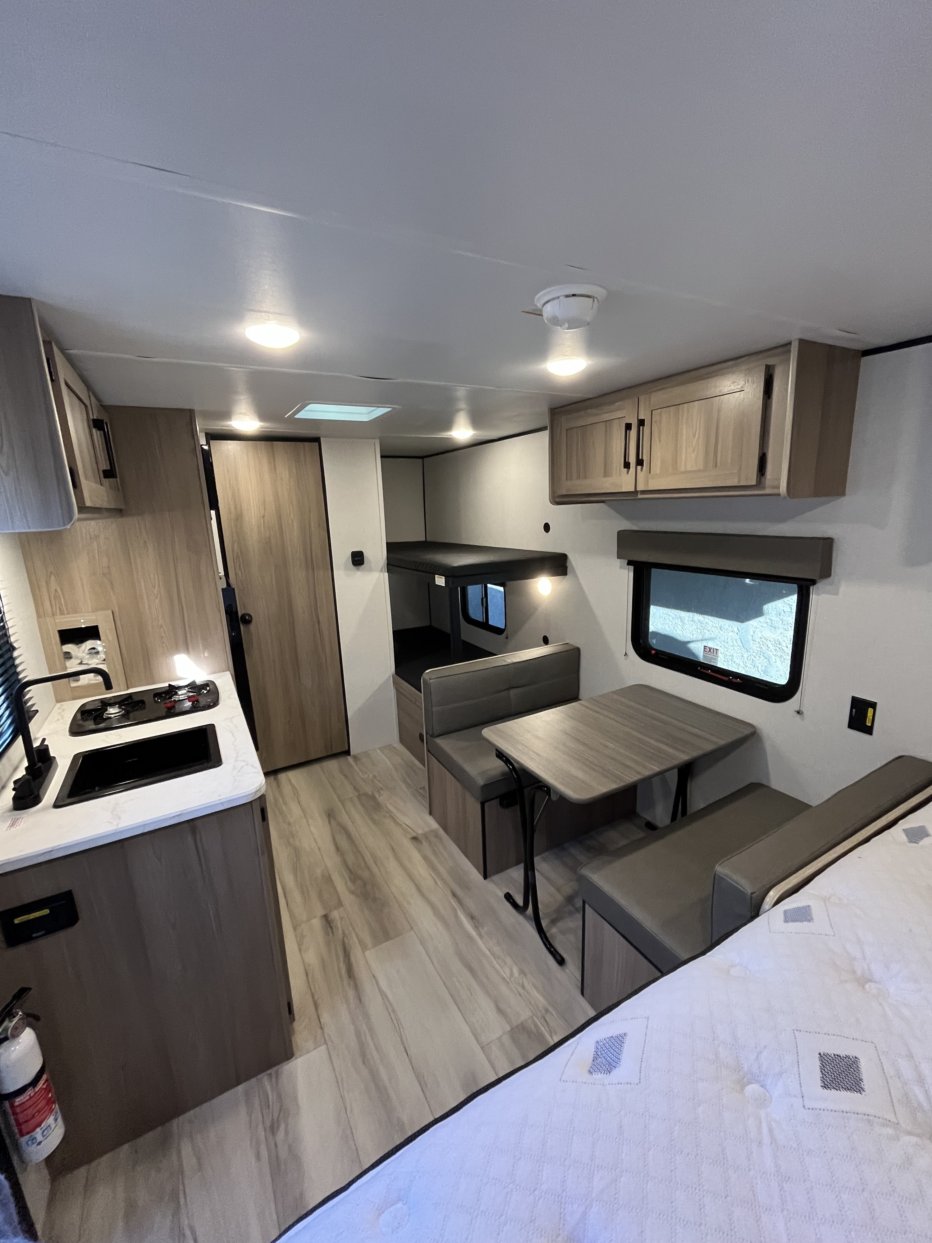 Modern rv rental interior with kitchenette, dinette, bunk beds, and a cozy bed in the foreground. Clean and functional.. Keystone RV Coleman 2025