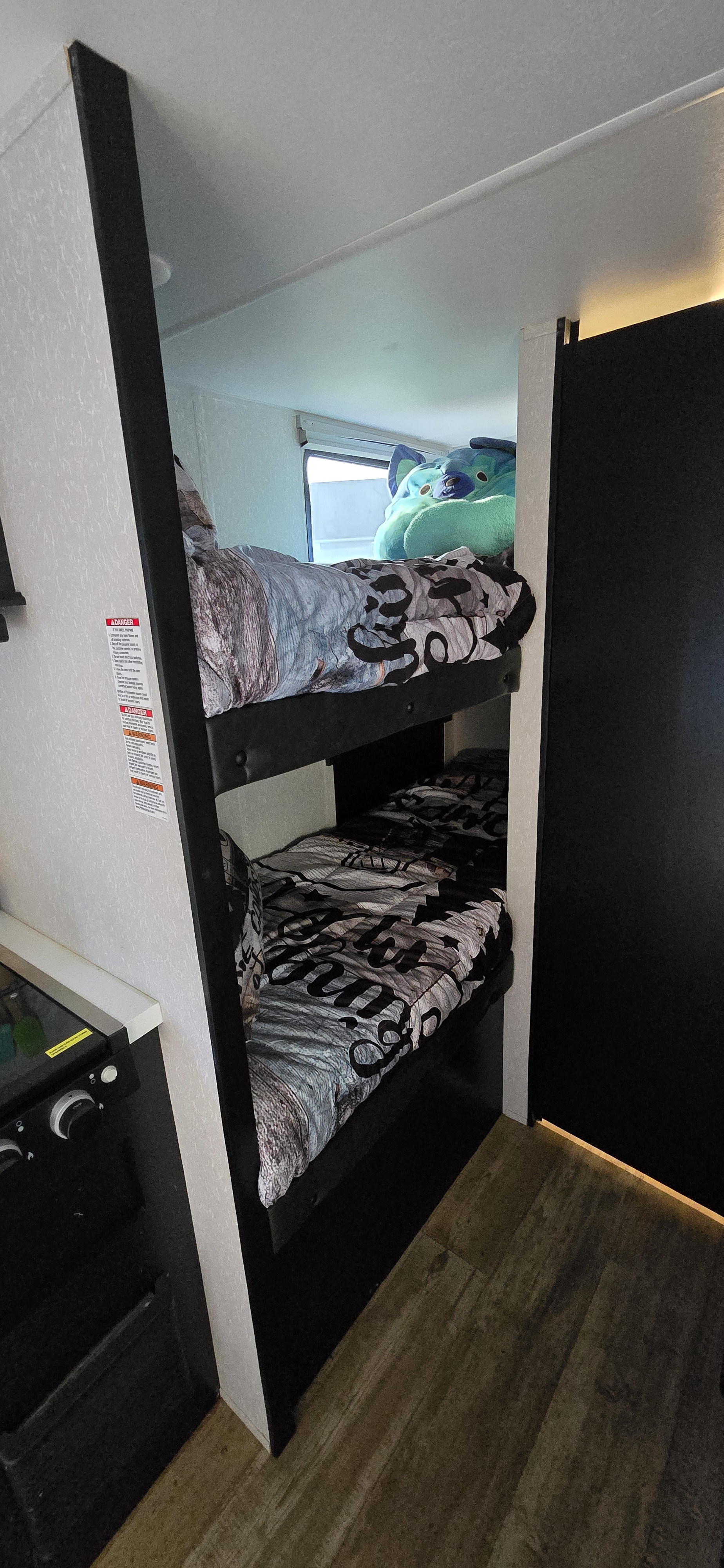 Inside an RV rental: two compact bunk beds with bedding and a stuffed animal, perfect for family trips.. Forest River Cherokee Wolf Pup Black Label 2021