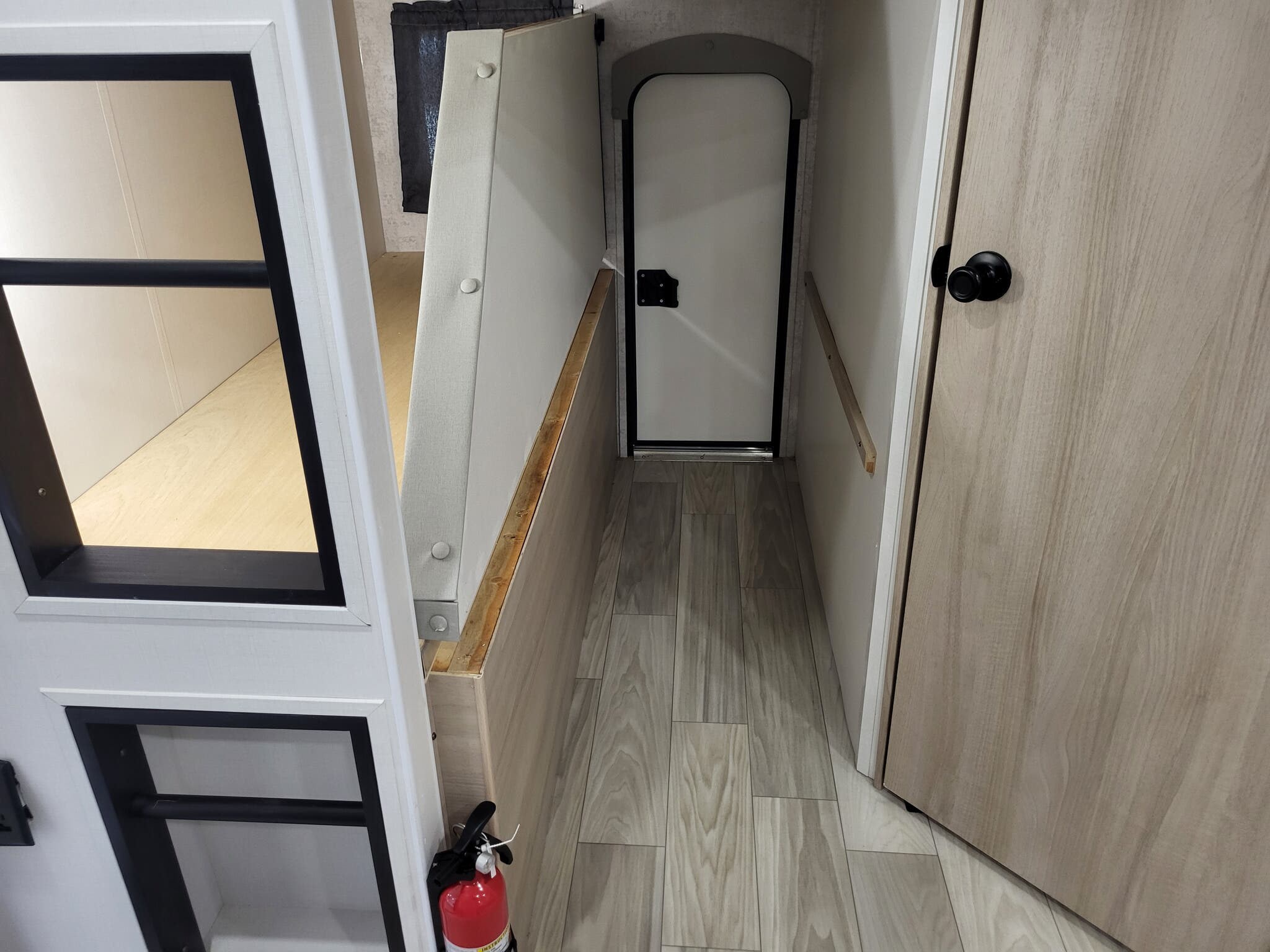 RV rental interior: Hallway with bunk beds, closed door, and fire extinguisher on light wood-look floor.. Winnebago Minnie Winnie 2023