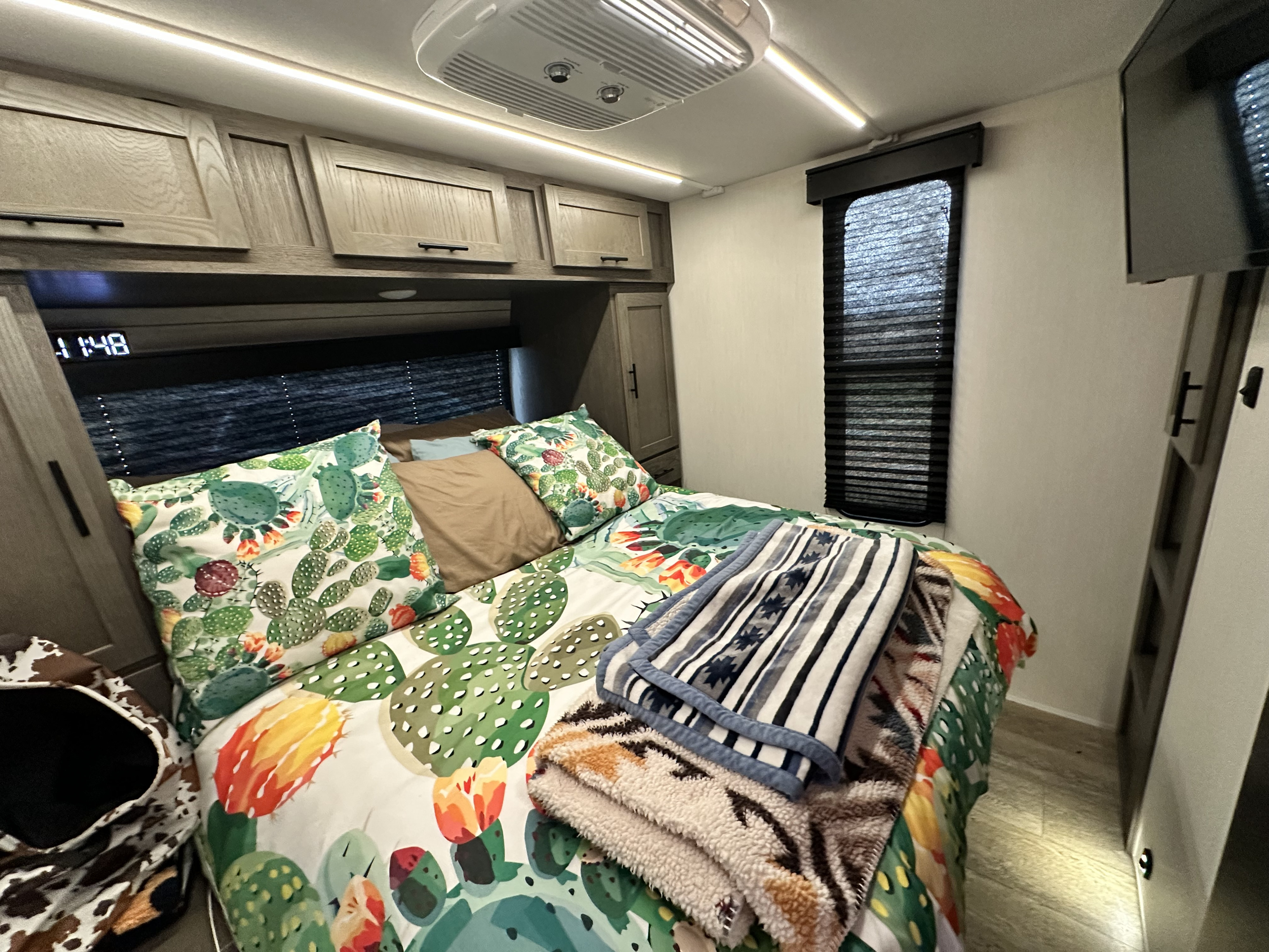 Cozy RV rental bedroom with cactus decor, bed, cabinets, window, and TV. Perfect for a comfortable stay.. Forest River Cherokee Alpha Wolf 2025