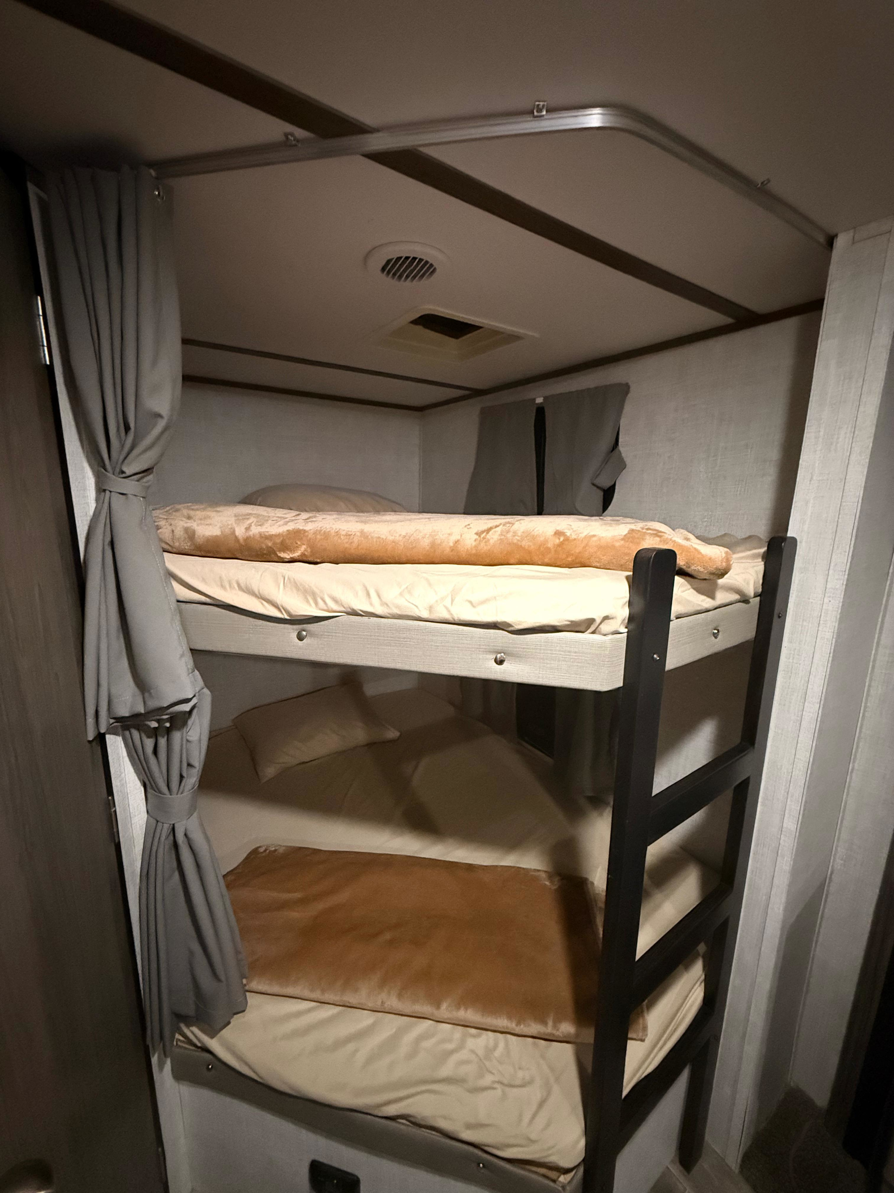Cozy RV rental bunk beds, featuring sleeping areas with sheets, blankets, privacy curtains, and ceiling vents for comfort.. Gulf Stream Streamlite Signature 2023