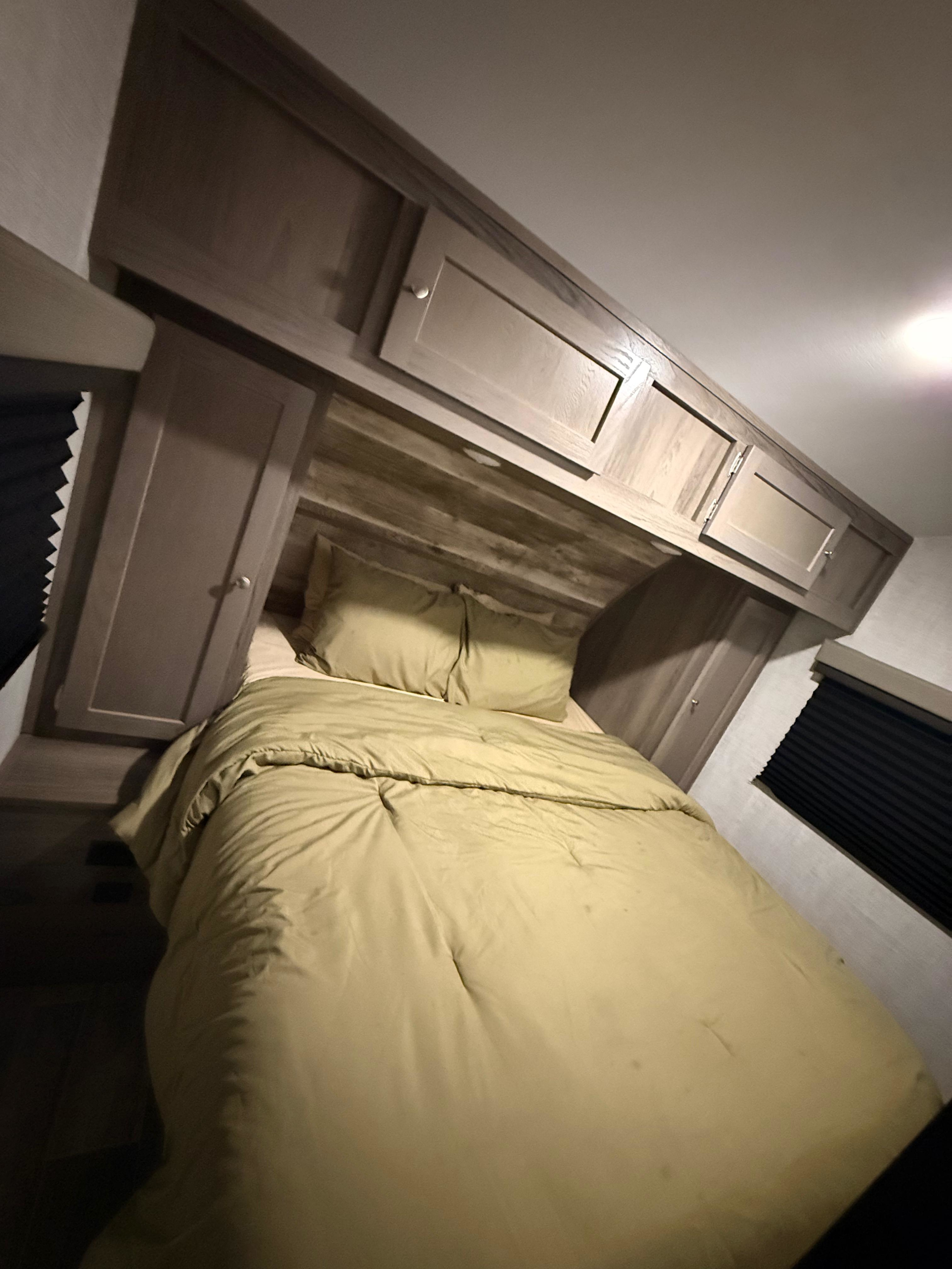 Cozy RV rental bedroom with a comfy bed, overhead cabinets, and window blinds, offering a compact sleeping area.. Gulf Stream Streamlite Signature 2023