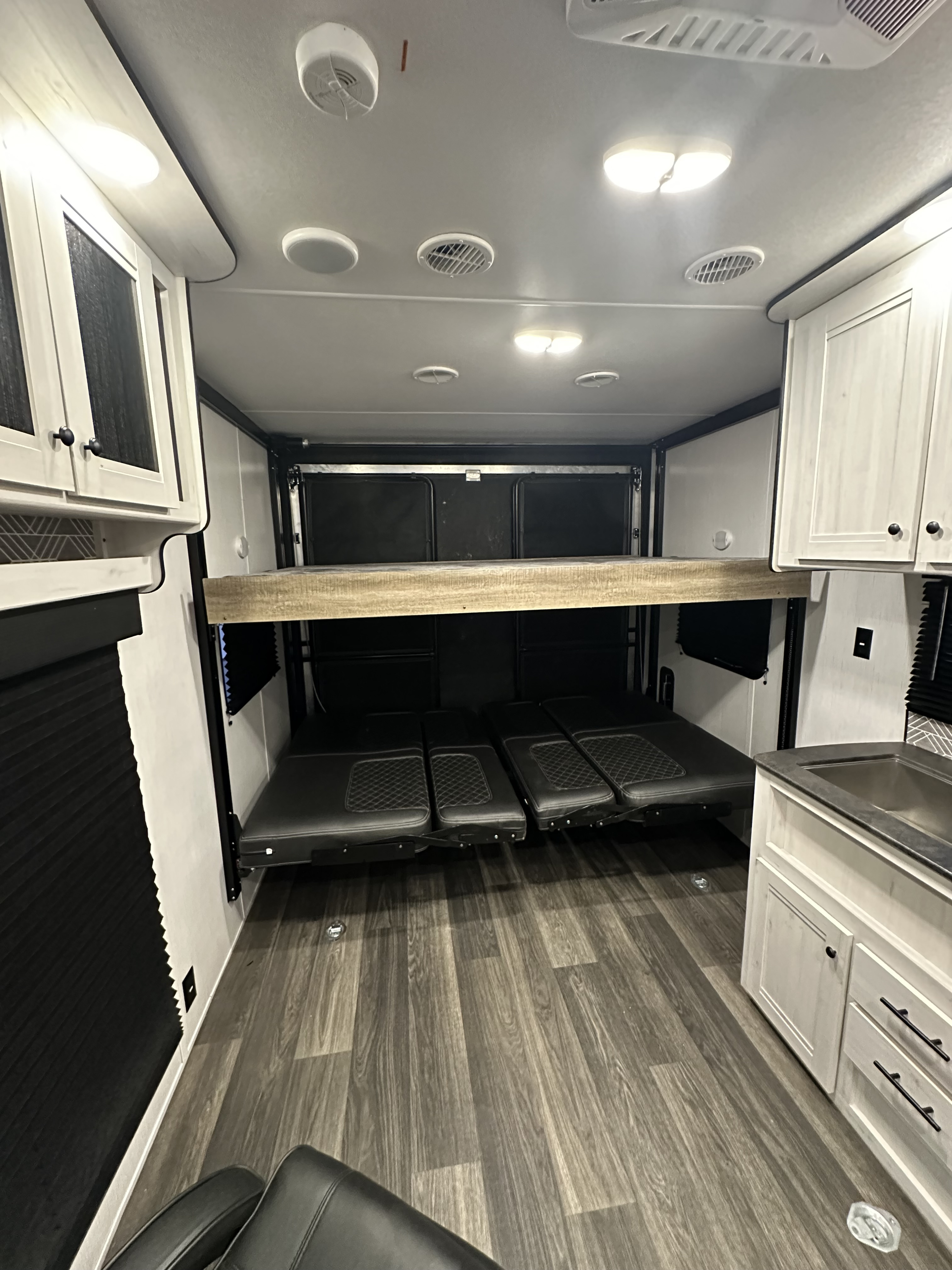 This RV rental interior features a bunk bed over convertible seating/bed, a modern kitchen counter, and wood-look flooring.. Heartland Lithium 2414 2023