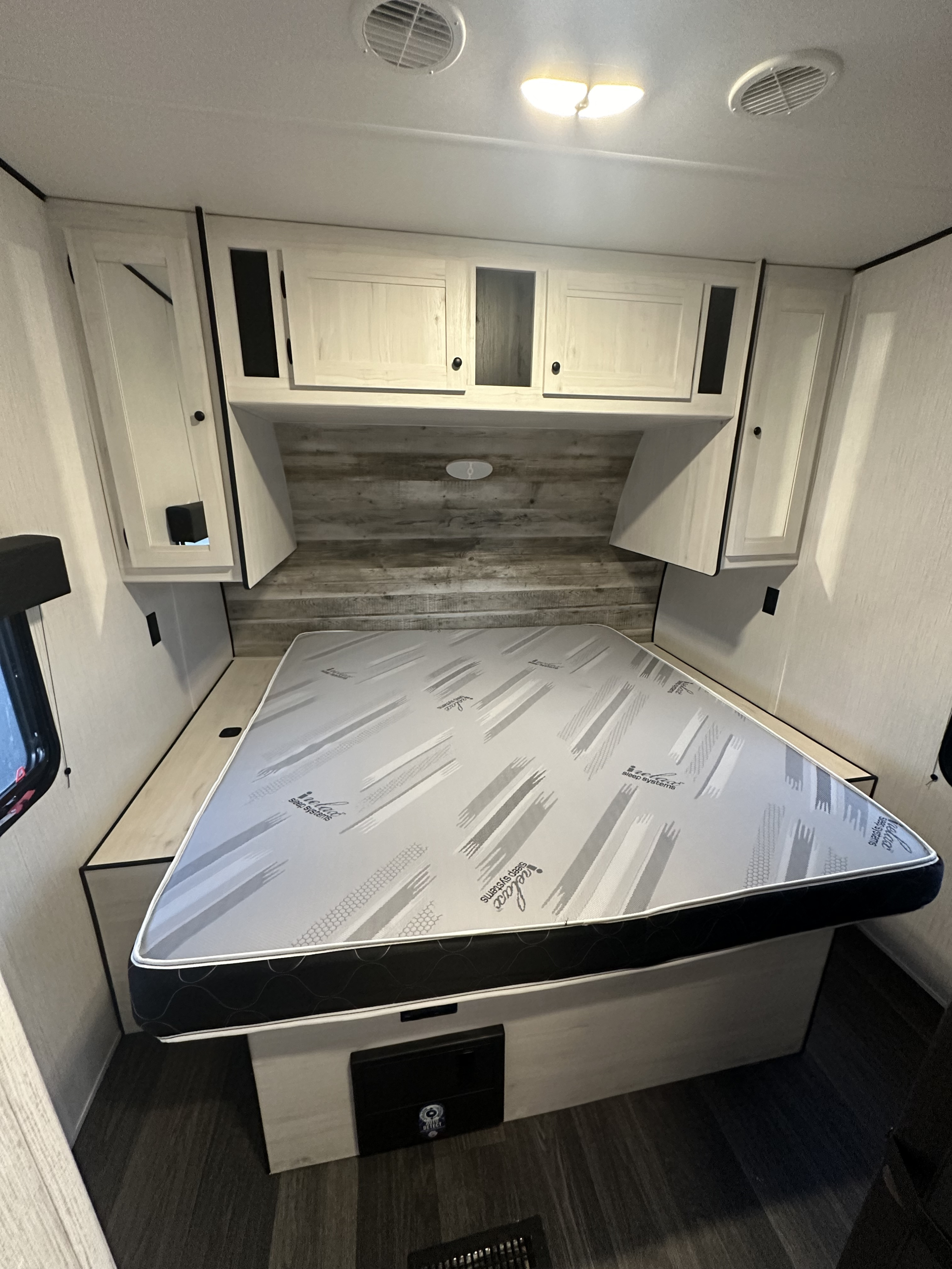 RV rental bedroom with a comfortable "Ielax Sleep Systems" mattress, overhead cabinets, and bright ceiling lights.. Heartland Lithium 2414 2023