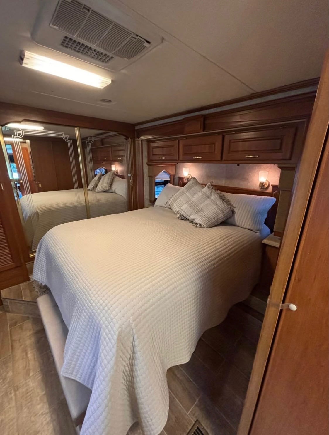Inside an RV rental, this inviting bedroom features a queen bed, overhead wood cabinets, and mirrored closet doors.. Beaver Santiam 2005
