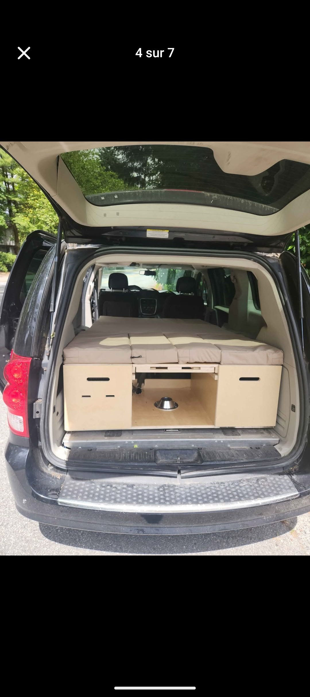 Minivan RV rental setup: rear view of a DIY camper conversion with a comfy bed, storage, and pet bowl ready for adventure.. Dodge B Van 2017