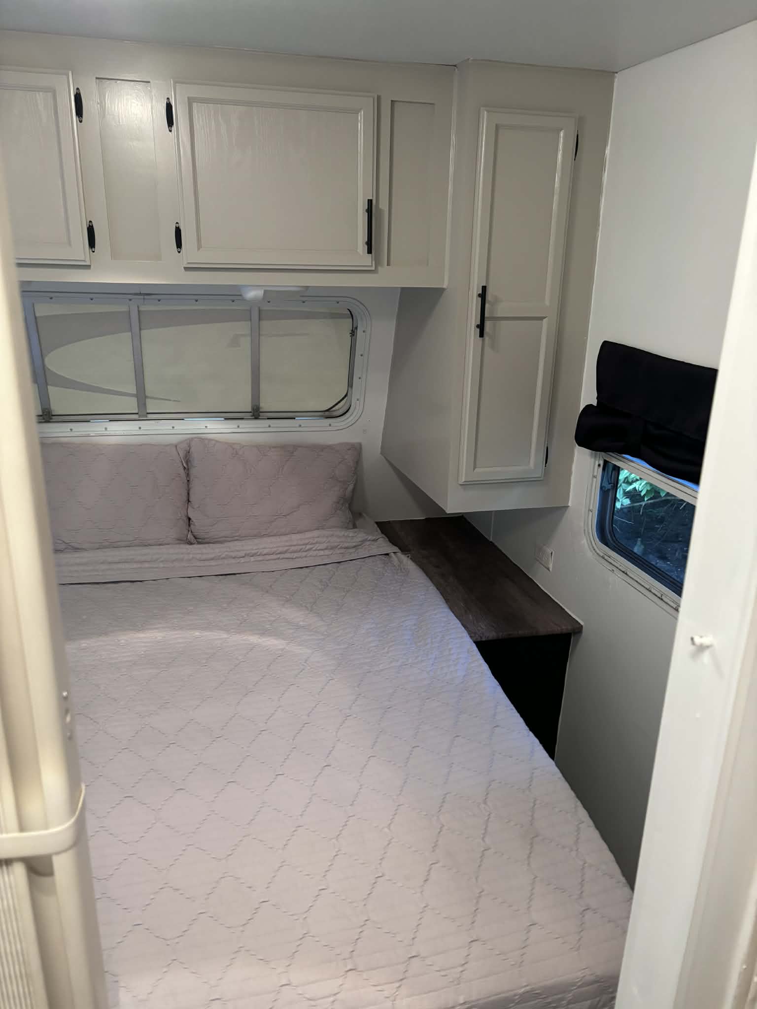 This cozy rv rental features a bedroom with a quilted bed, overhead storage, and windows, designed for comfortable travel.. Jayco Jay Flight 2004