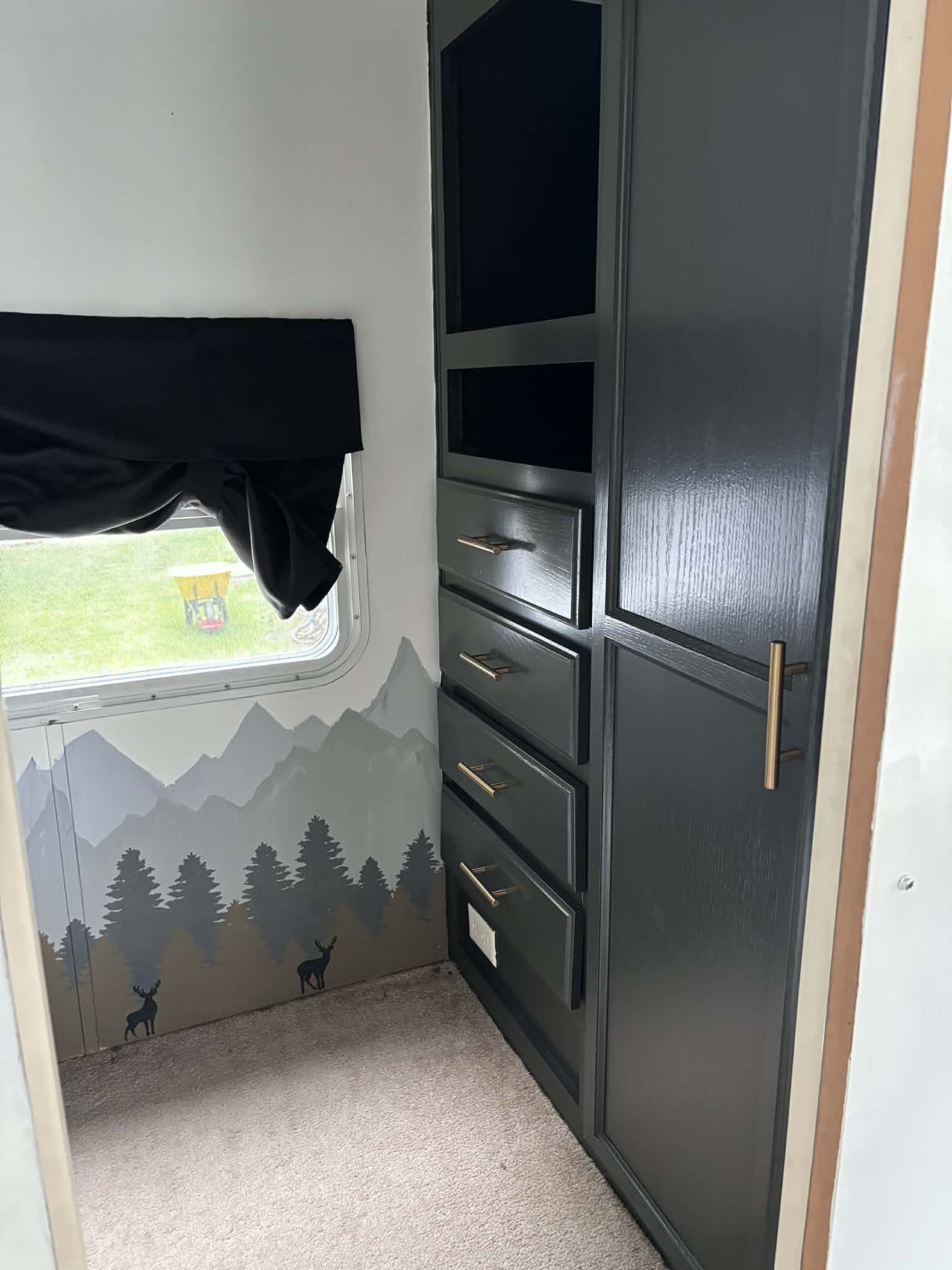 RV rental interior showcasing sleek black cabinets with gold pulls, a nature-themed mural, and cozy carpet.. Jayco Jay Flight 2004
