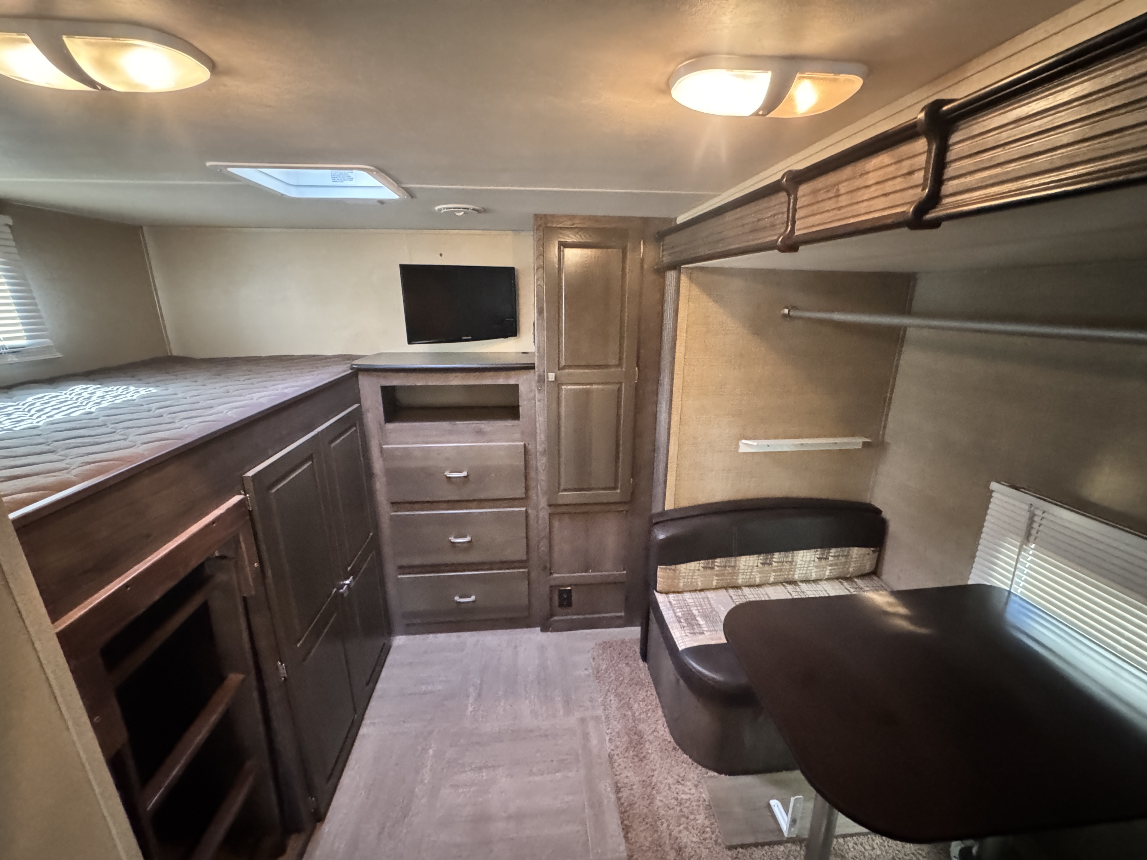Interior of an rv rental showing a comfortable bunk bed, dinette with table, wall-mounted TV, and built-in storage.. Dutchmen Kodiak 2015