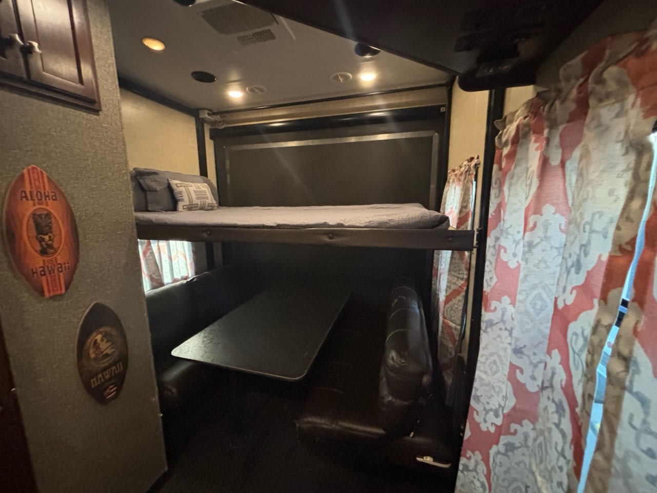 RV rental interior: Cozy bunk beds over a dinette seating area, with Hawaiian decor. Perfect for family travel.. Heartland RVs Road Warrior Toy Hauler 2015