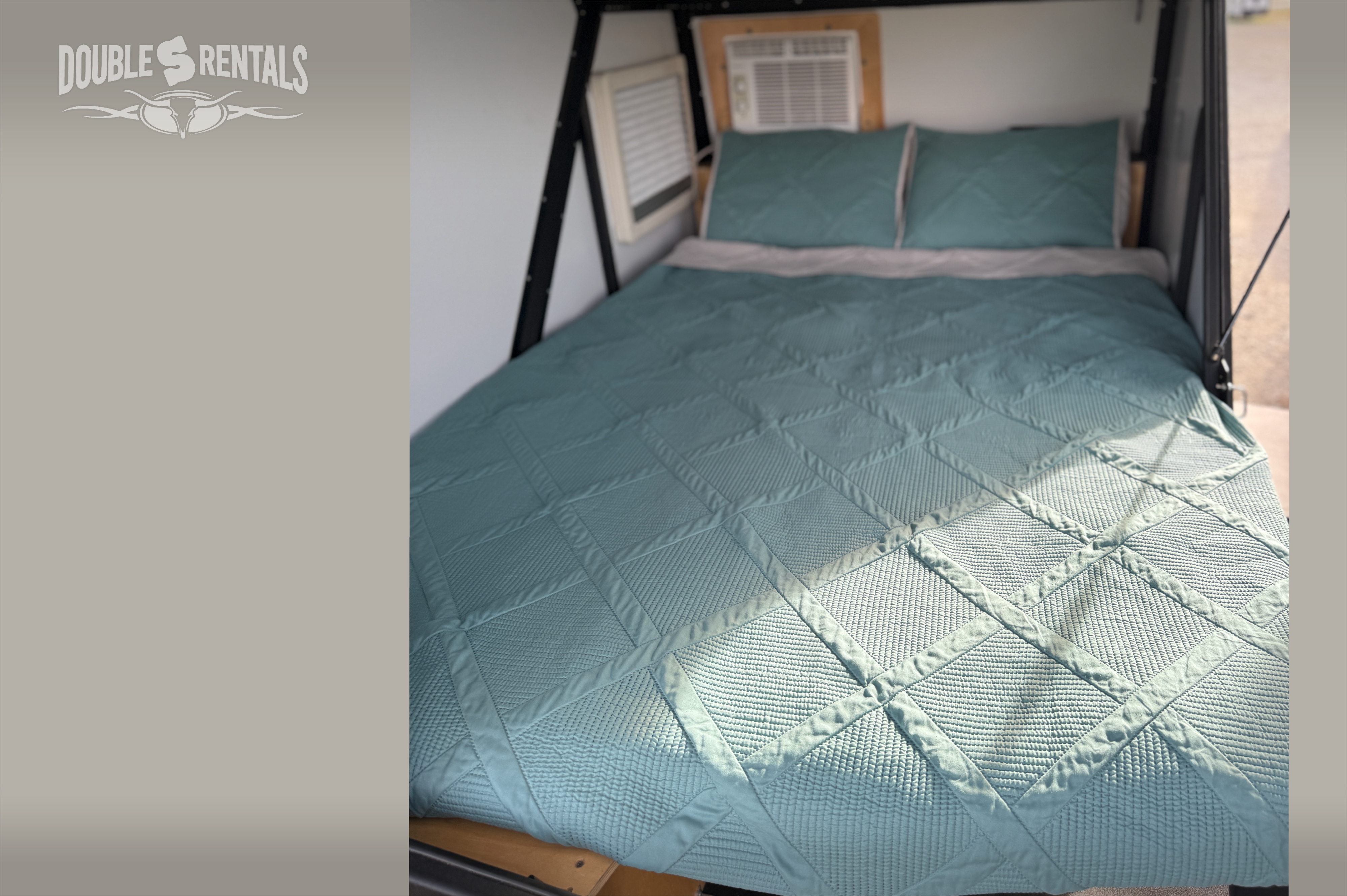 Inside our RV rental: A comfy bed with a quilted teal bedspread, pillows, and AC for your trip.. TAXA TigerMoth 2023