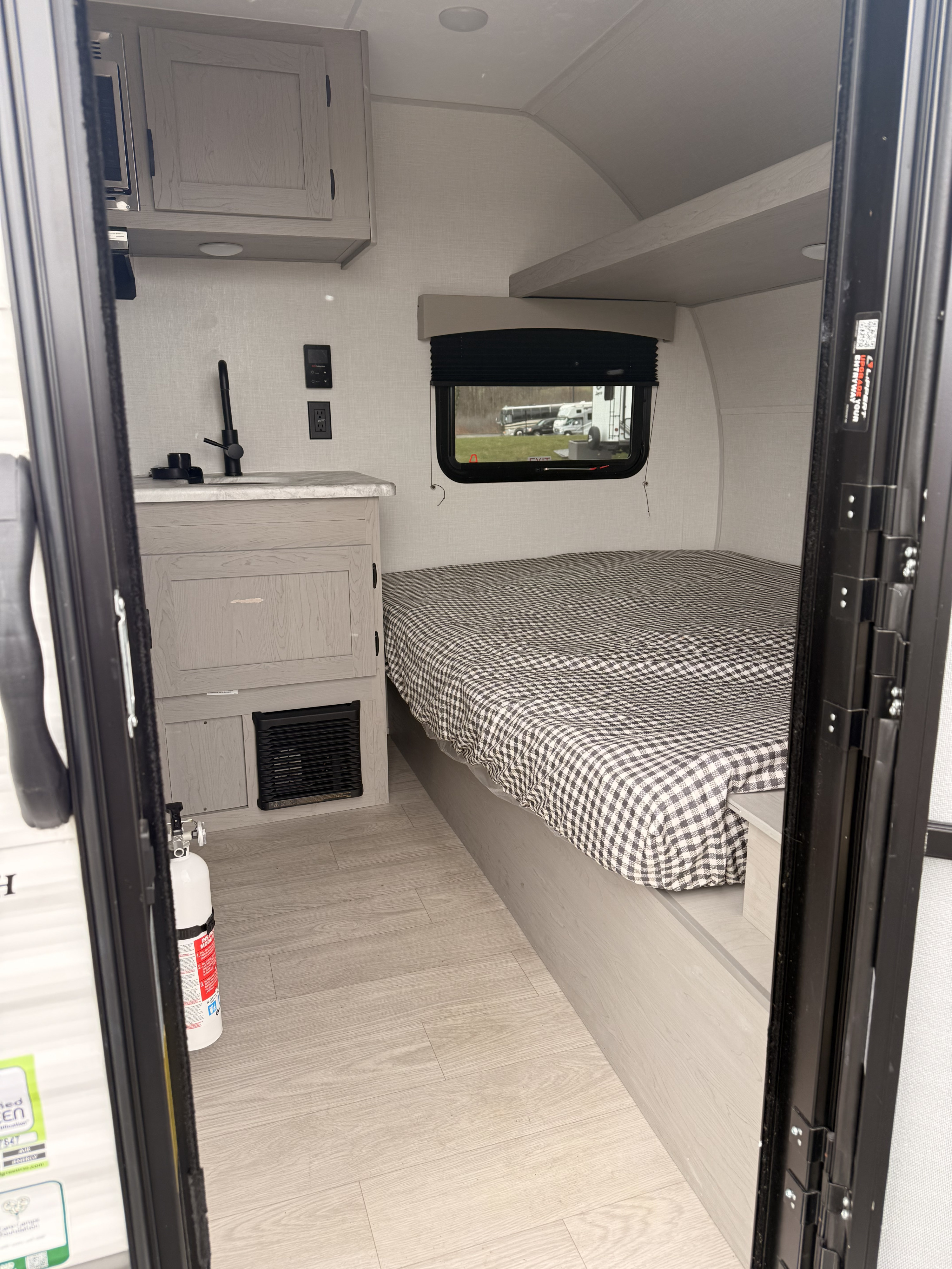 Step into this modern RV rental: a compact interior with a checkered bed, functional kitchen, and light wood floors.. Coachman Clipper 2026