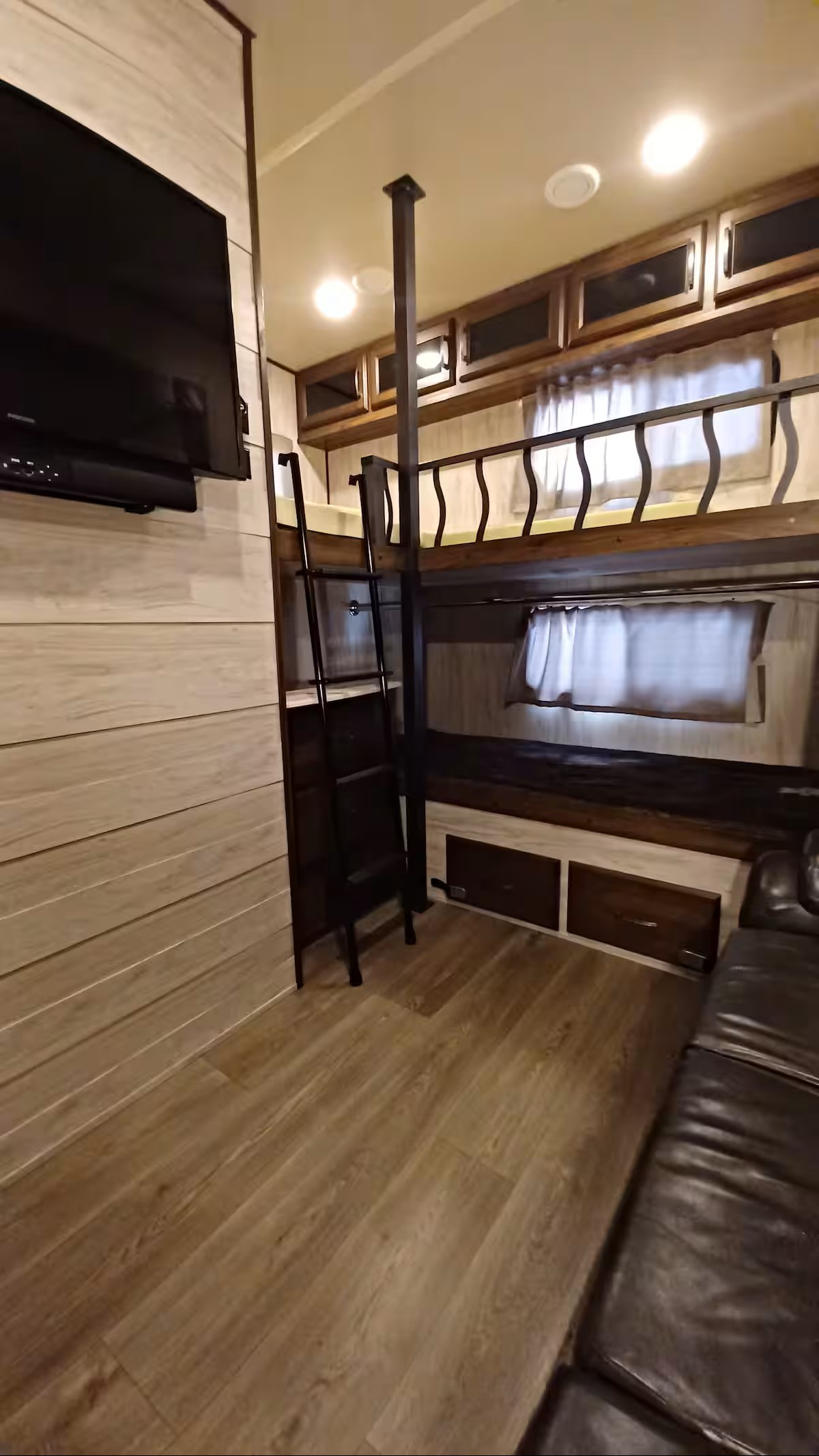 Cozy RV rental interior with bunk beds, TV, and a leather couch, showcasing comfortable camper living.. Forest River Palomino Columbus C-Series 2019