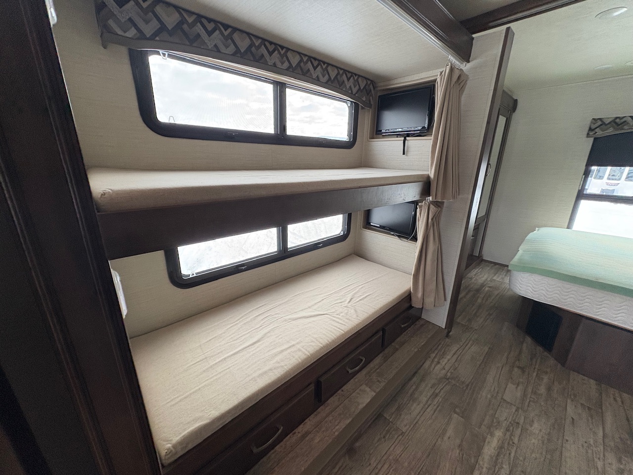 RV rental sleeping area: double bunk beds with individual TVs, windows & curtains. Master bed visible.. Jayco Alante 2018