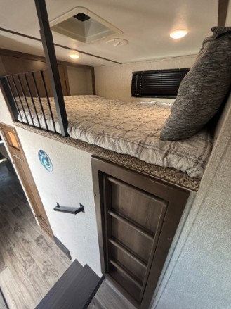 An RV rental's clever interior features a cozy loft bed with a protective railing, a ladder for access, and storage below.. Keystone RV Sprinter 2019