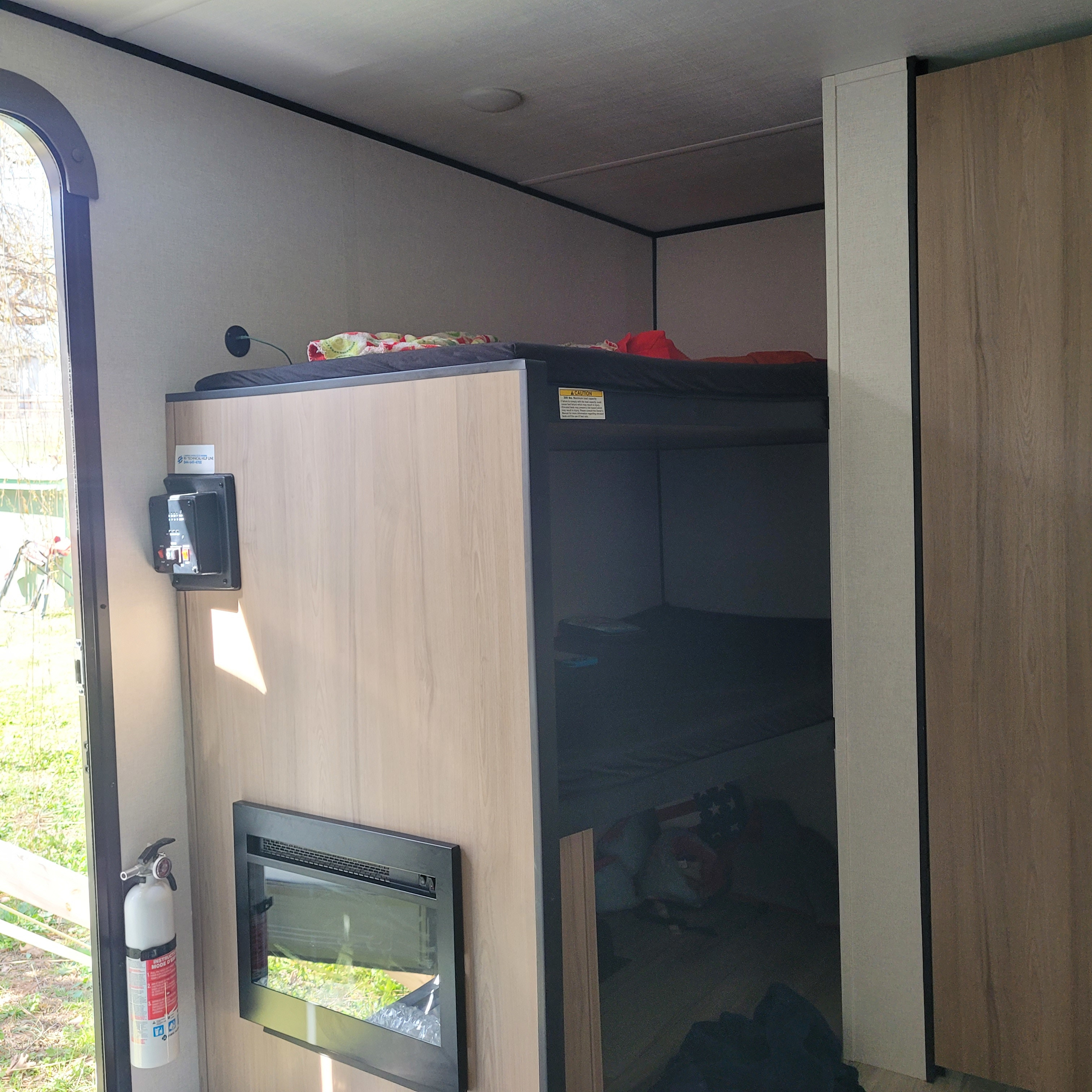 Cozy rv rental interior featuring built-in bunk beds, an electric fireplace, and a mounted fire extinguisher by the door.. 4YDTCME14TM937831 13B 2026