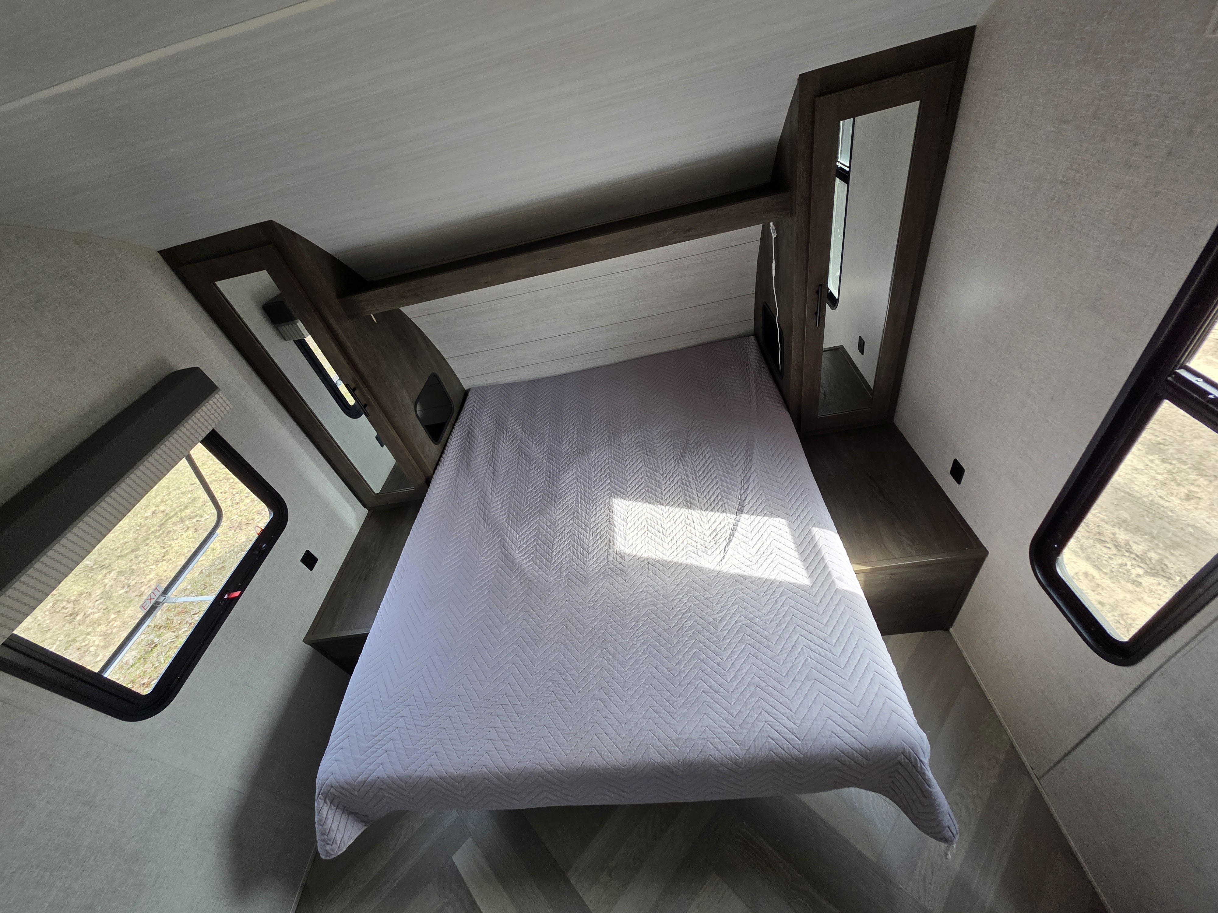 **rv rental** bedroom: light gray chevron-quilted bed, dark wood built-ins, and windows. Modern and comfortable interior.. Forest River Salem Cruise Lite 2021