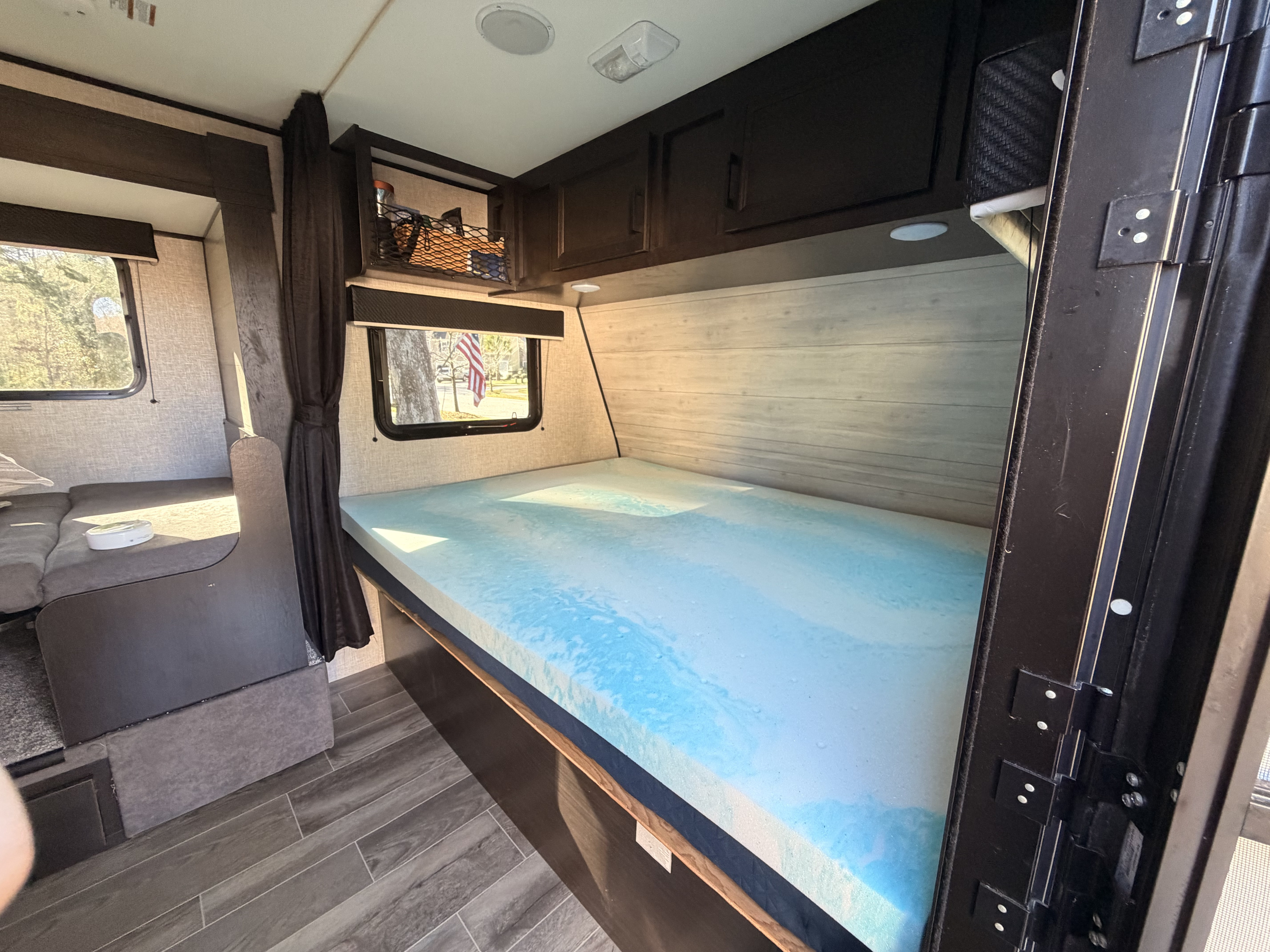 Inside an RV rental: a bedroom with a blue gel memory foam topper, overhead storage, and dinette seating. Ready for travel.. Jayco Jay Flight SLX 2022
