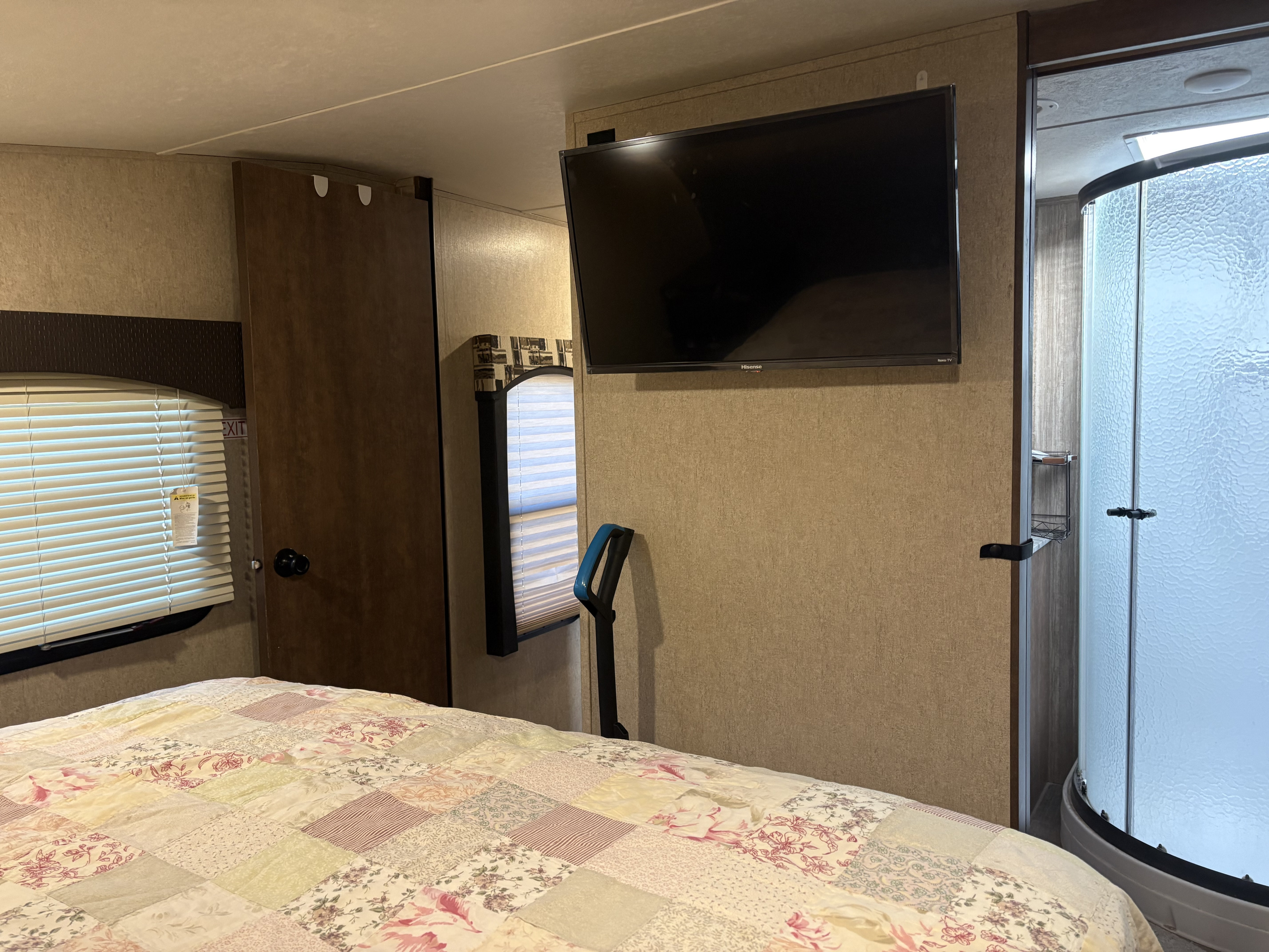 RV rental bedroom interior with a cozy bed, wall-mounted TV, and a compact shower, showing efficient use of space.. Starcraft Solstice Super Lite 2018