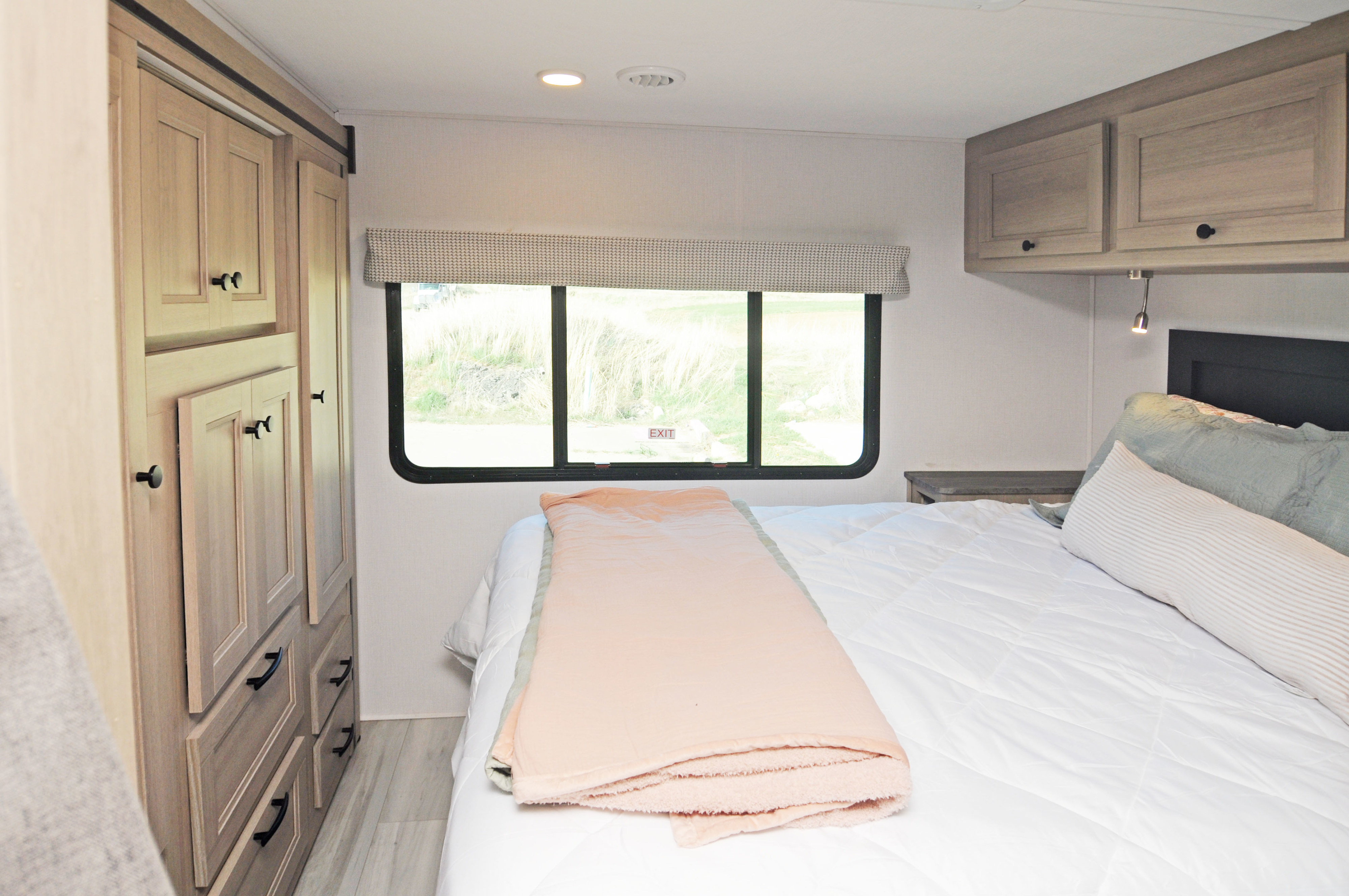 Cozy RV rental bedroom with ample storage, a comfortable bed, and scenic window views. Perfect for your next travel adventure!. Forest River Sunseeker LE 2025