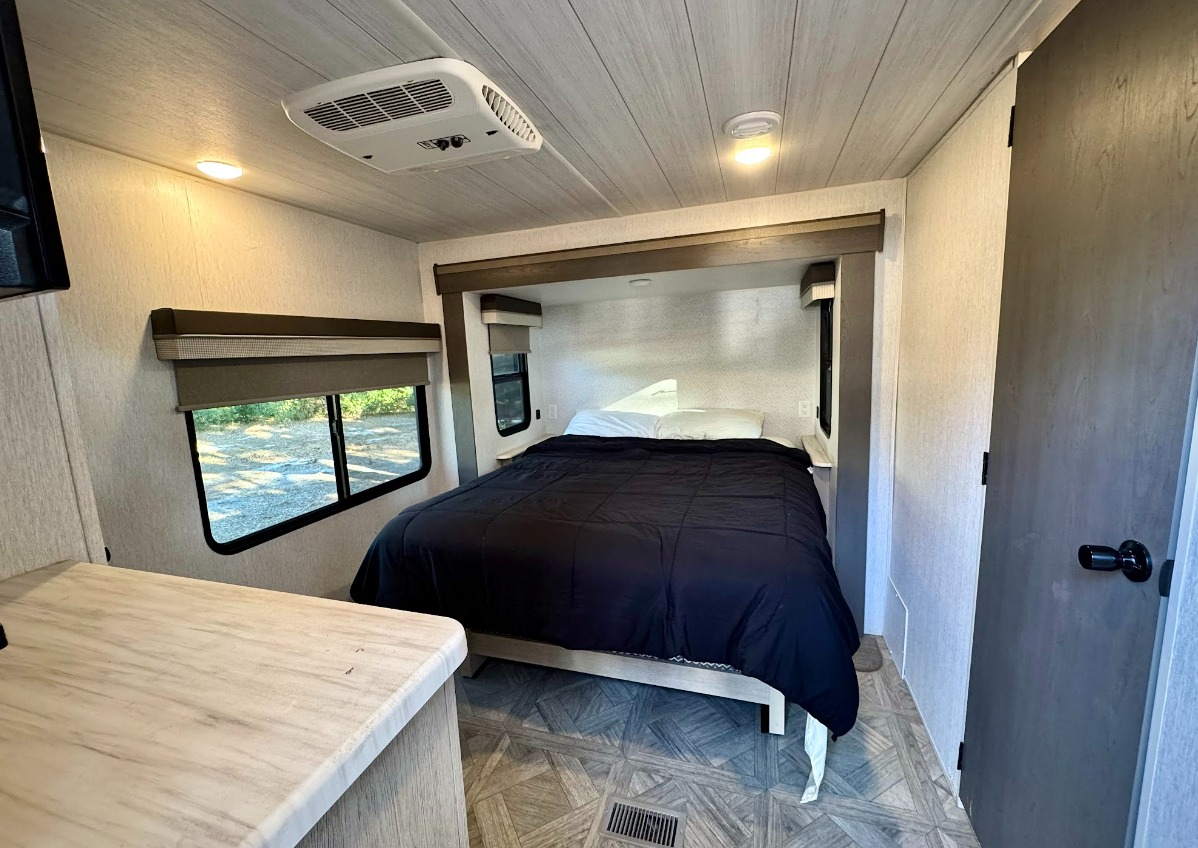 Cozy RV rental bedroom featuring a queen bed, large windows, AC unit, and modern decor. Ideal for your next adventure.. Salem 36VBDS 2024