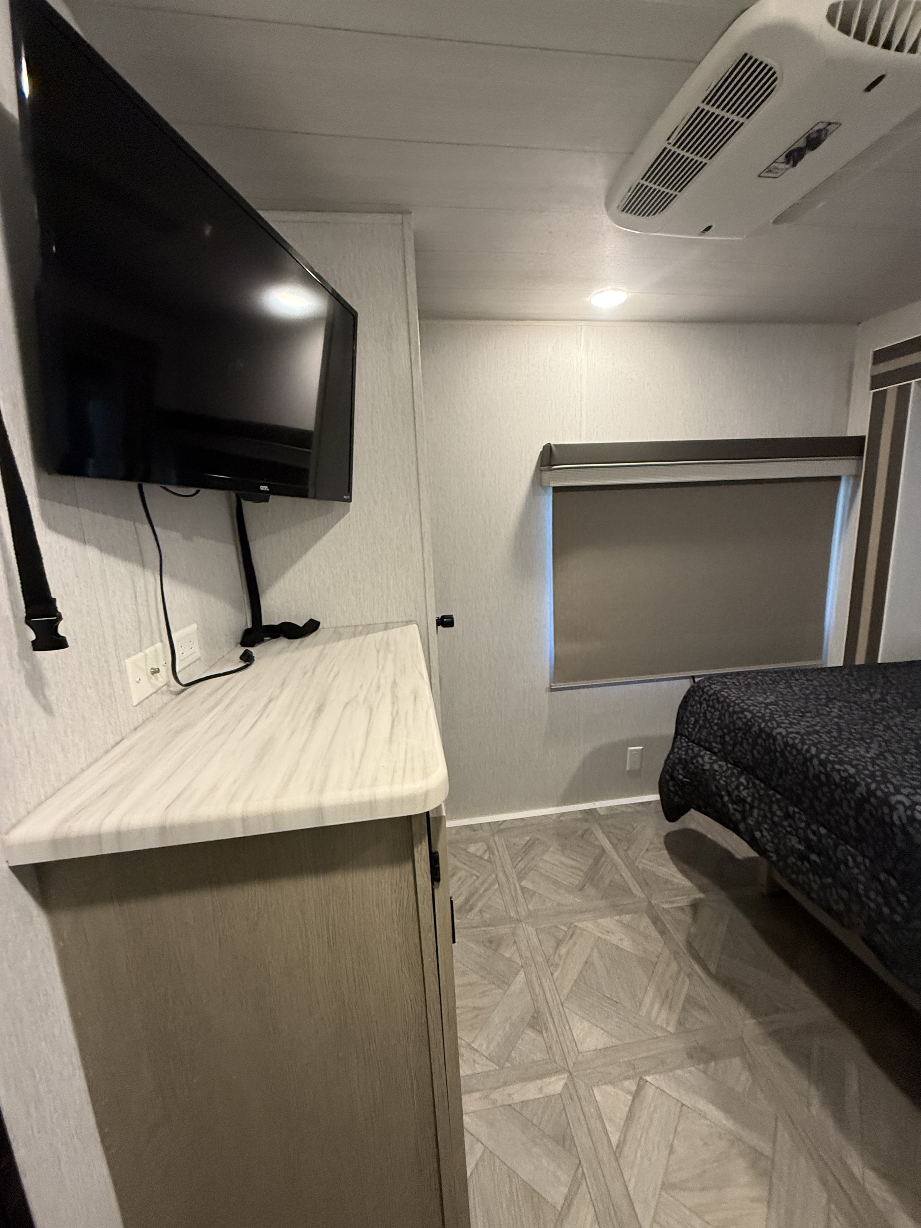 Modern RV rental bedroom interior with wall-mounted TV, window, bed, and AC unit, ideal for comfortable travel.. Salem 36VBDS 2023