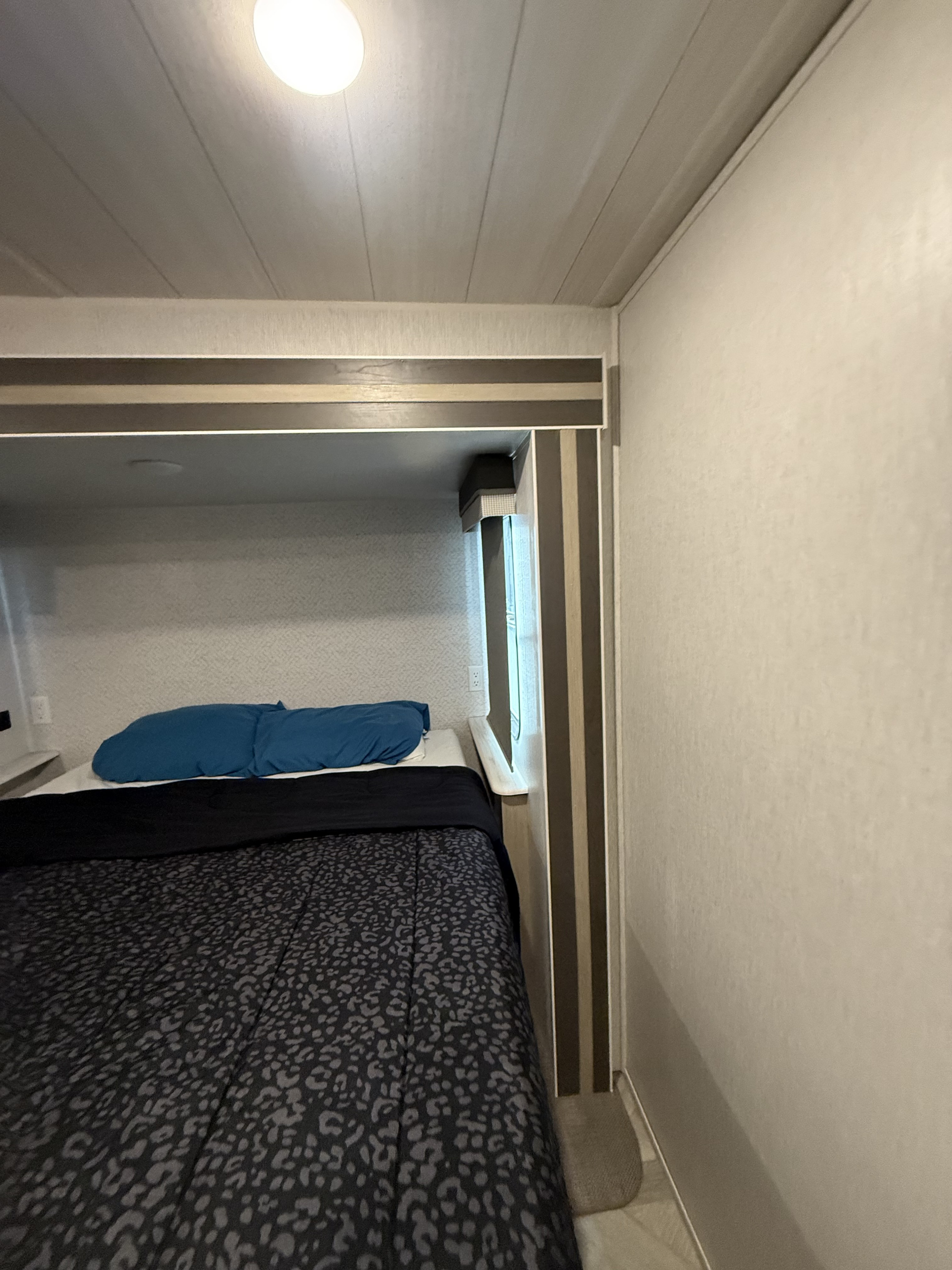 Cozy rv rental bunk bed bedroom with patterned comforter and blue pillow, providing compact sleeping.. Salem 36VBDS 2023