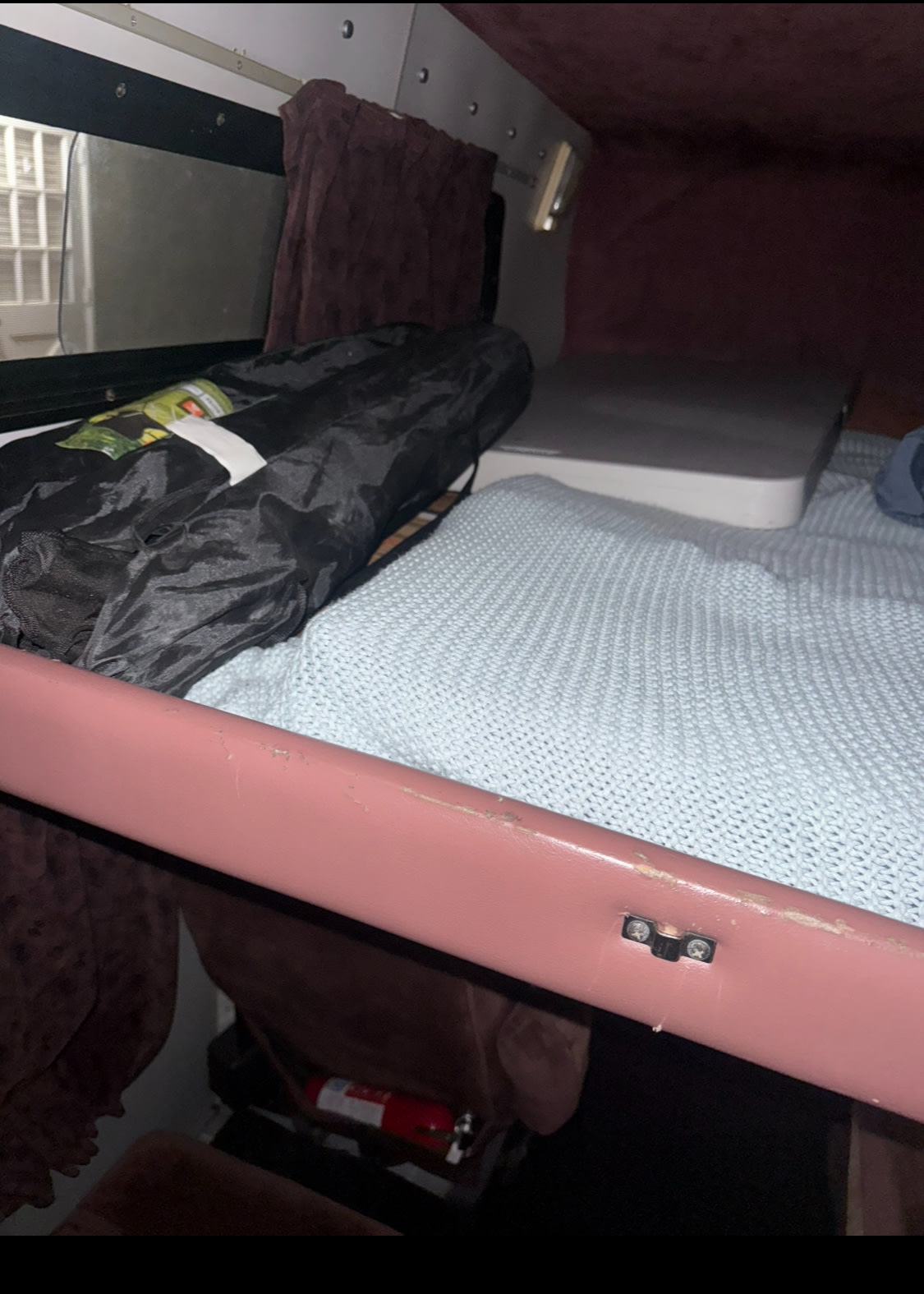 RV rental bunk bed with a light blue blanket, rolled black bag, window, and fire extinguisher below. Ready for adventure.. Dodge B Van 1998