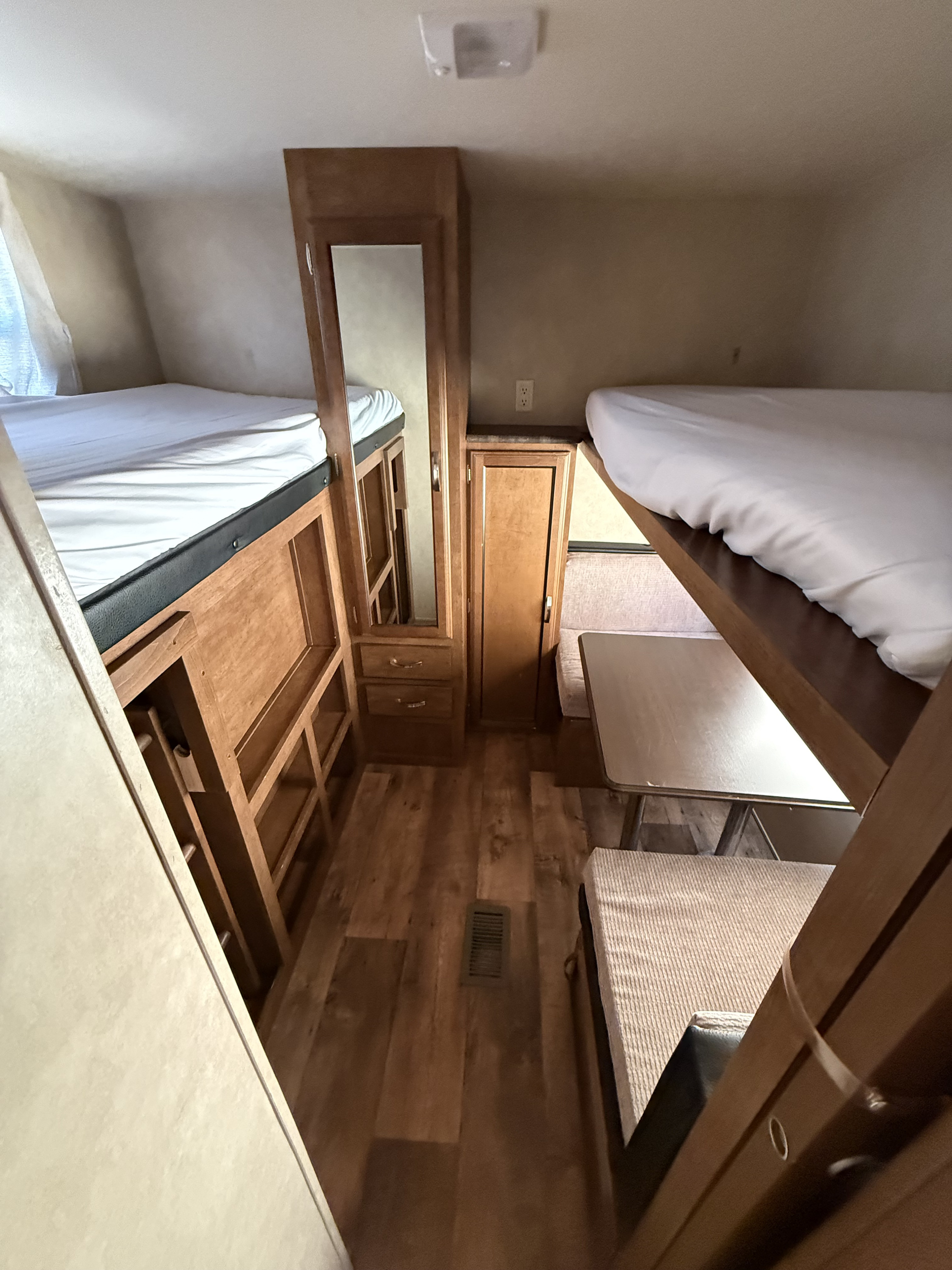 Cozy rv rental interior featuring bunk beds, a dinette area, and wooden cabinetry with a mirror. Ideal for family trips.. Forest River Wildwood 2016