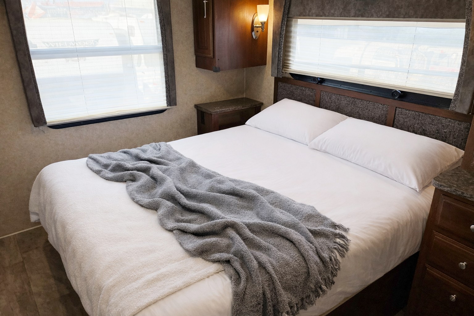 Comfortable RV rental bedroom featuring a neatly made bed with white pillows and a soft gray blanket, ready for rest.. Forest River Georgetown 2016