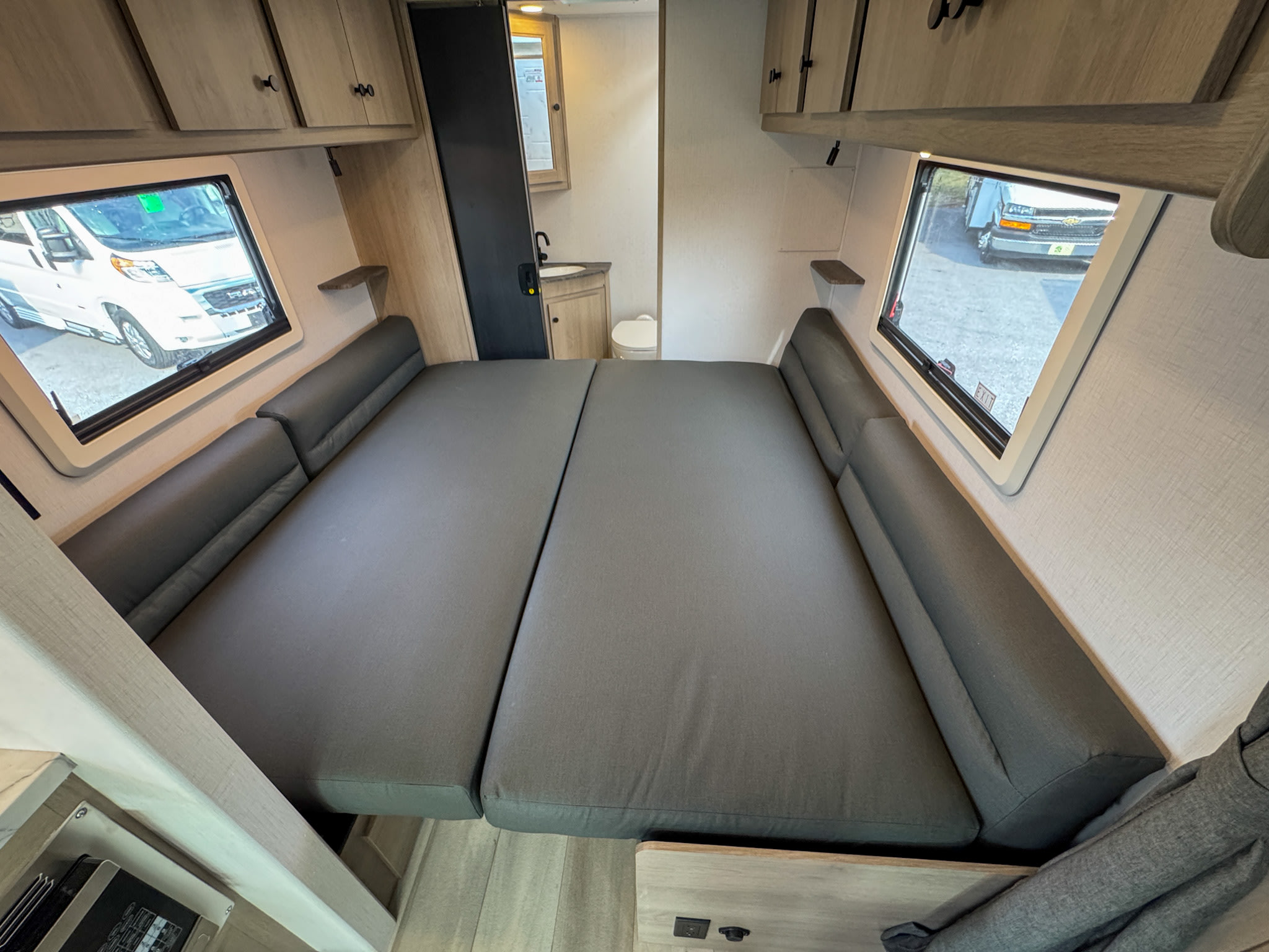RV rental interior: A cozy convertible bed area with a visible bathroom and windows, perfect for your camper van adventure.. Forest River Sunseeker 2027