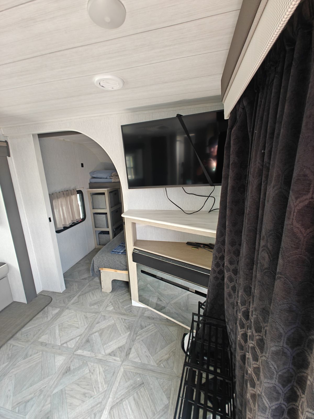 Cozy RV rental living space with TV, patterned floor, and arched entry to the bedroom. Great for travel.. Forest River Salem 2024