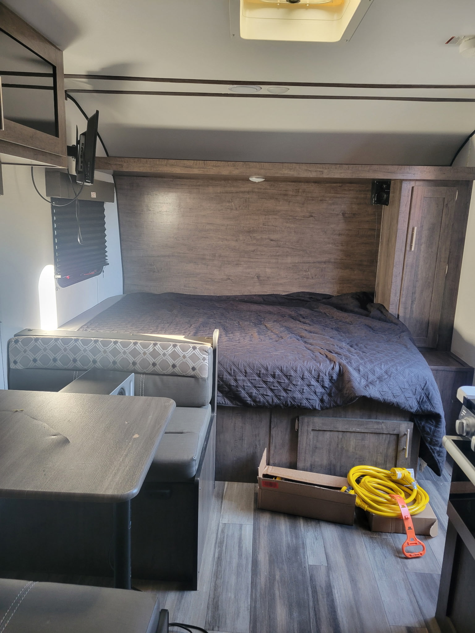 RV rental interior features a cozy bed, dinette, and TV. Wood-look cabinetry and flooring complete the space.. Riverside RV Retro 2022