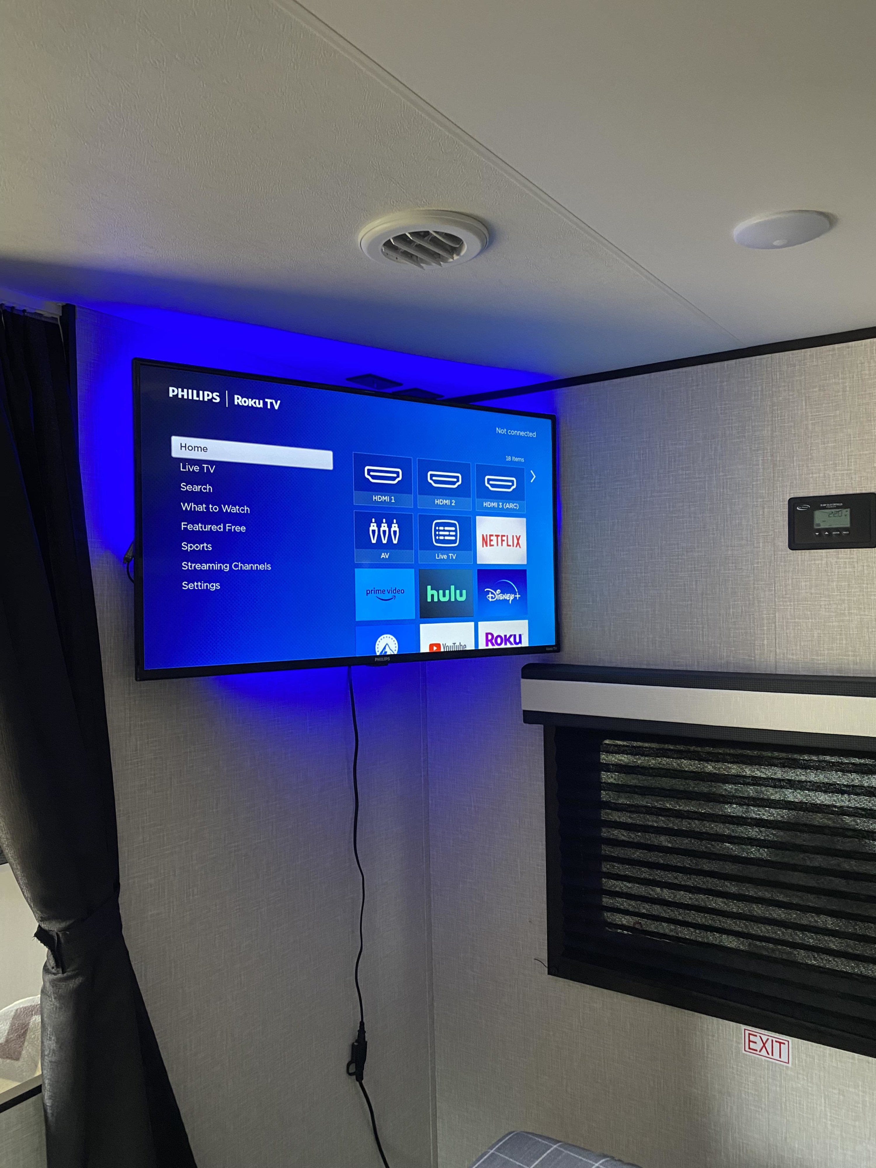 Philips Roku TV in an RV rental, displaying streaming apps like Netflix and Hulu, enhanced by blue LED backlighting. RV amenities visible.. Jayco Jay Flight 2024
