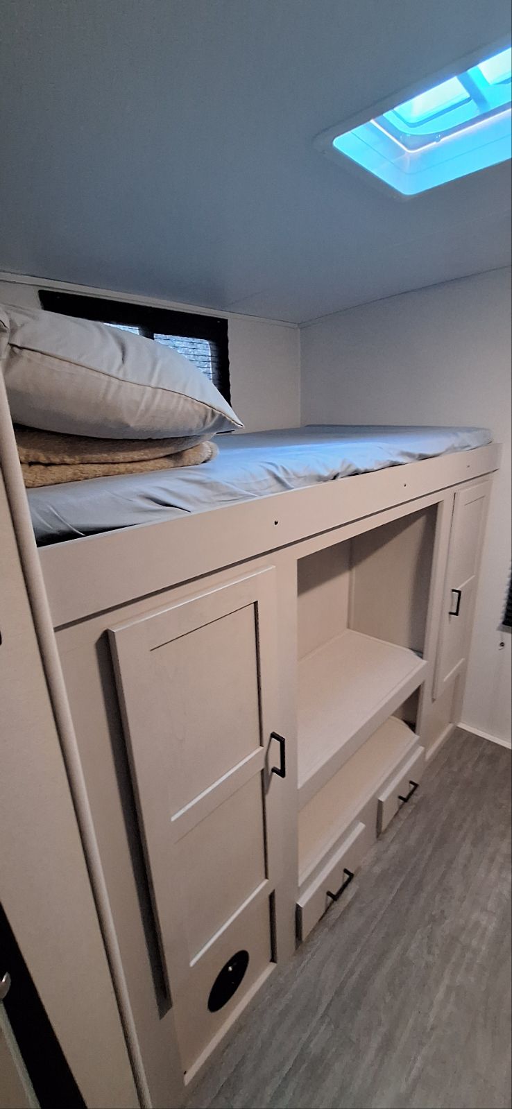 RV rental interior with bunk beds, light blue sheets, storage cabinets, window with blinds, and a ceiling skylight.. Heartland Mallard M32 2024