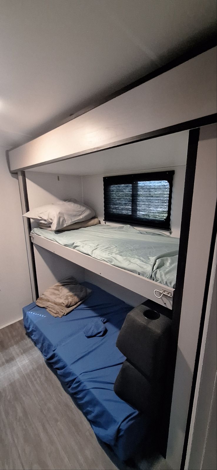 Compact bunk beds in an RV rental, complete with blue bedding, pillows, & a window with blinds. Ideal for travel accommodation.. Heartland Mallard M32 2024
