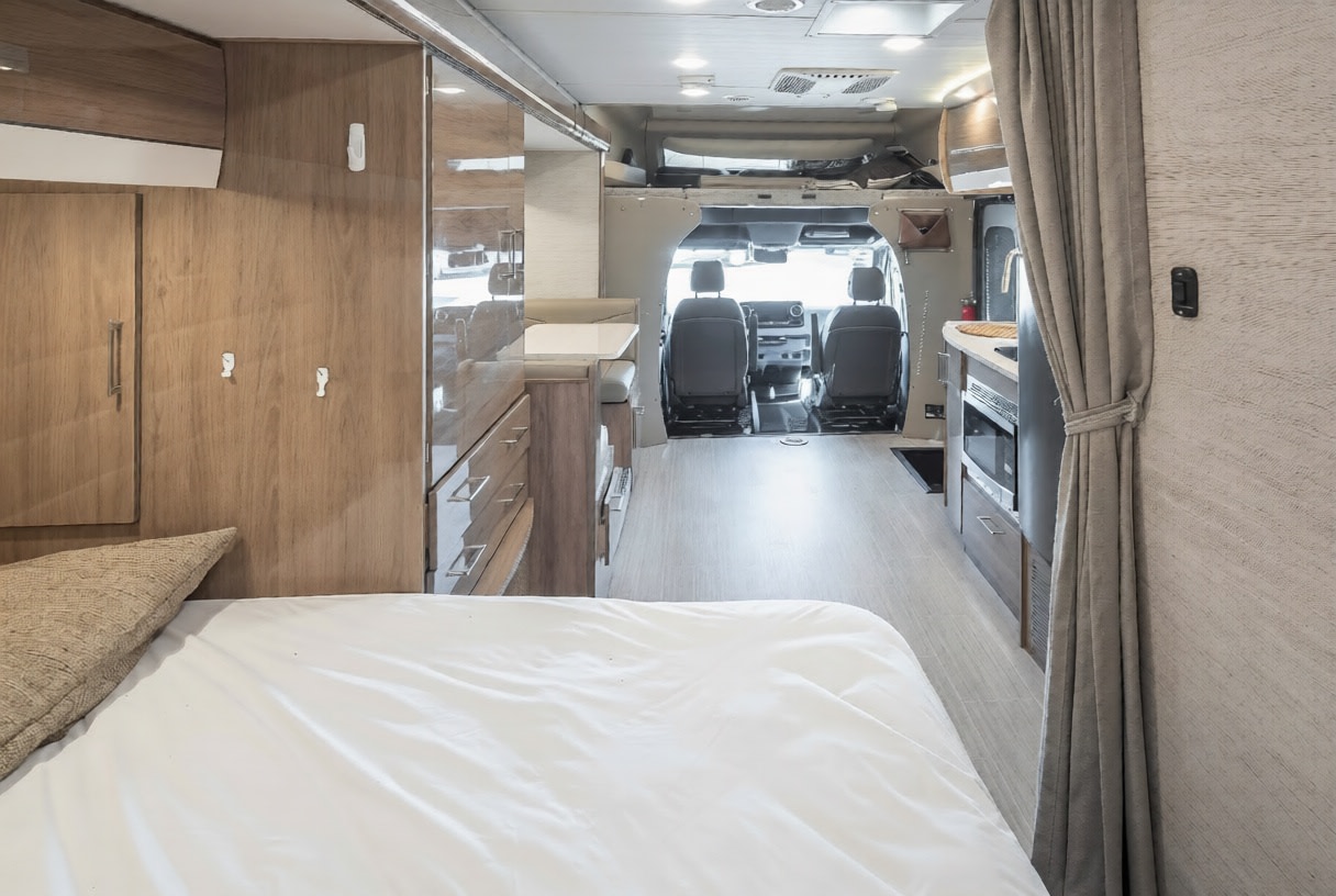 RV rental interior: bed, wood cabinetry, kitchen with microwave, and cockpit area, showcasing a compact and functional space.. Jayco Melbourne Prestige 2021