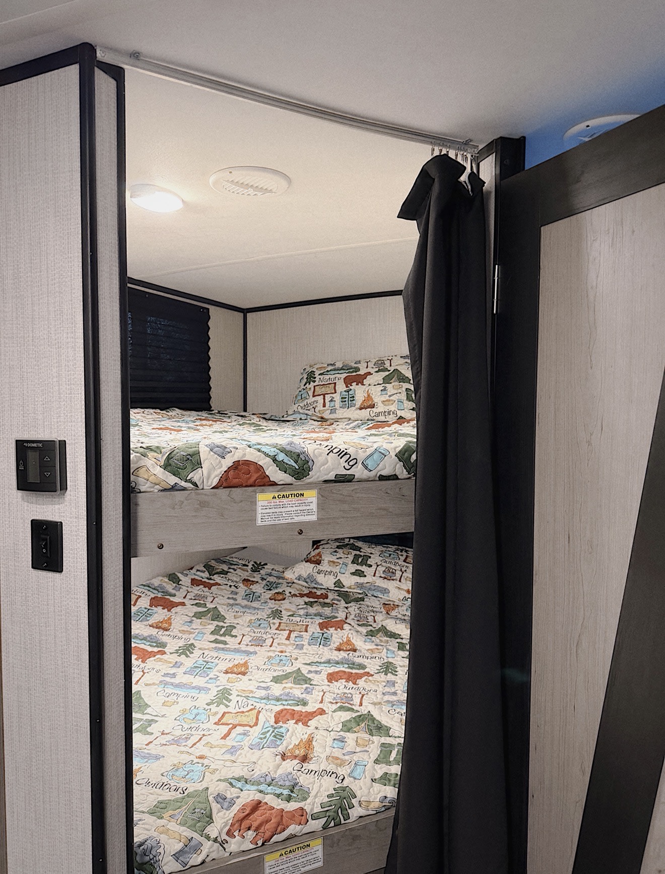 RV rental interior with cozy bunk beds, camping-themed bedding, and a privacy curtain, perfect for families.. Heartland RVs Mallard 2021