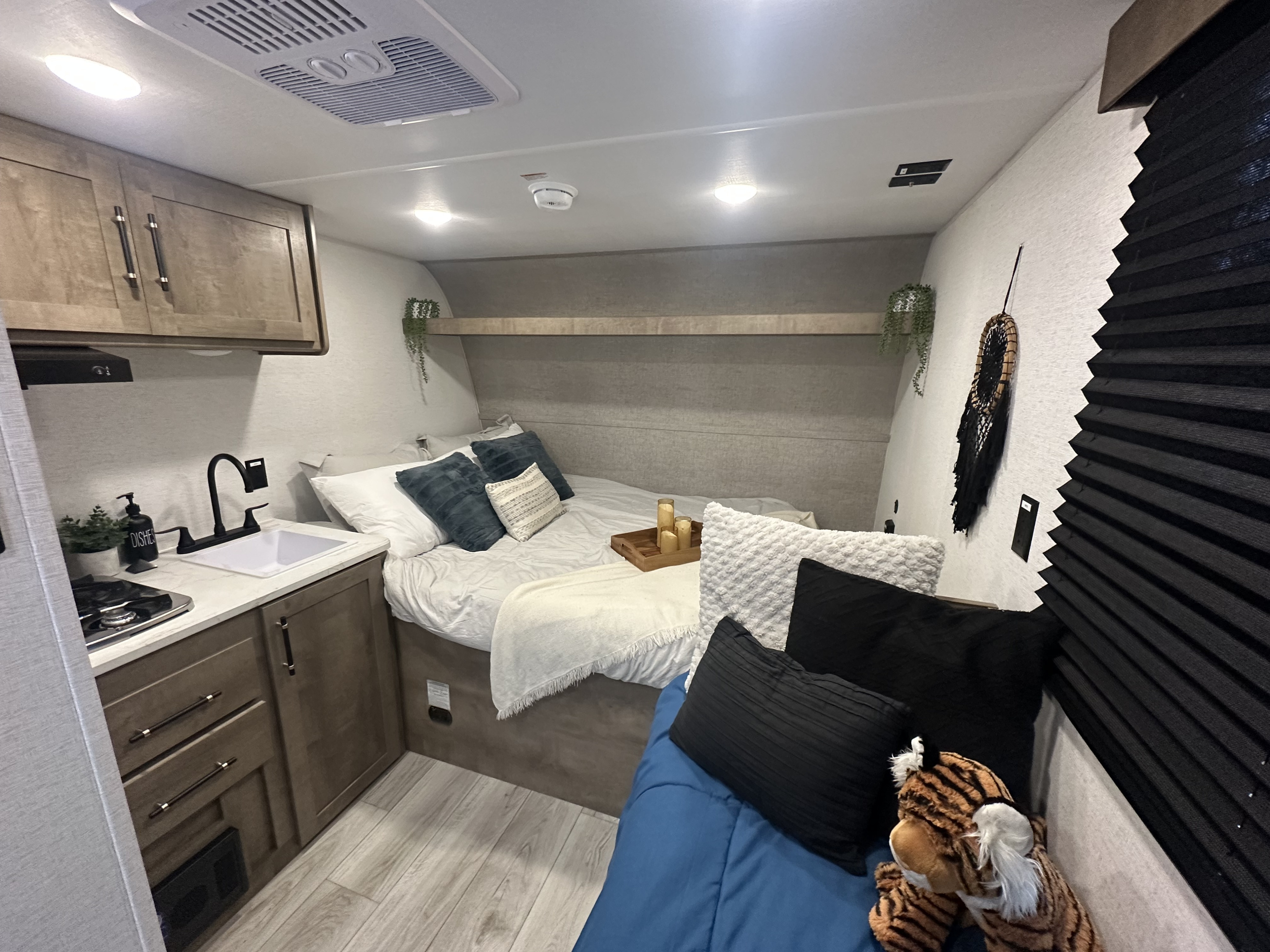 Cozy rv rental interior featuring a compact kitchen, comfortable bed, and living area with a plush tiger.. Keystone RV Springdale Mini 2025