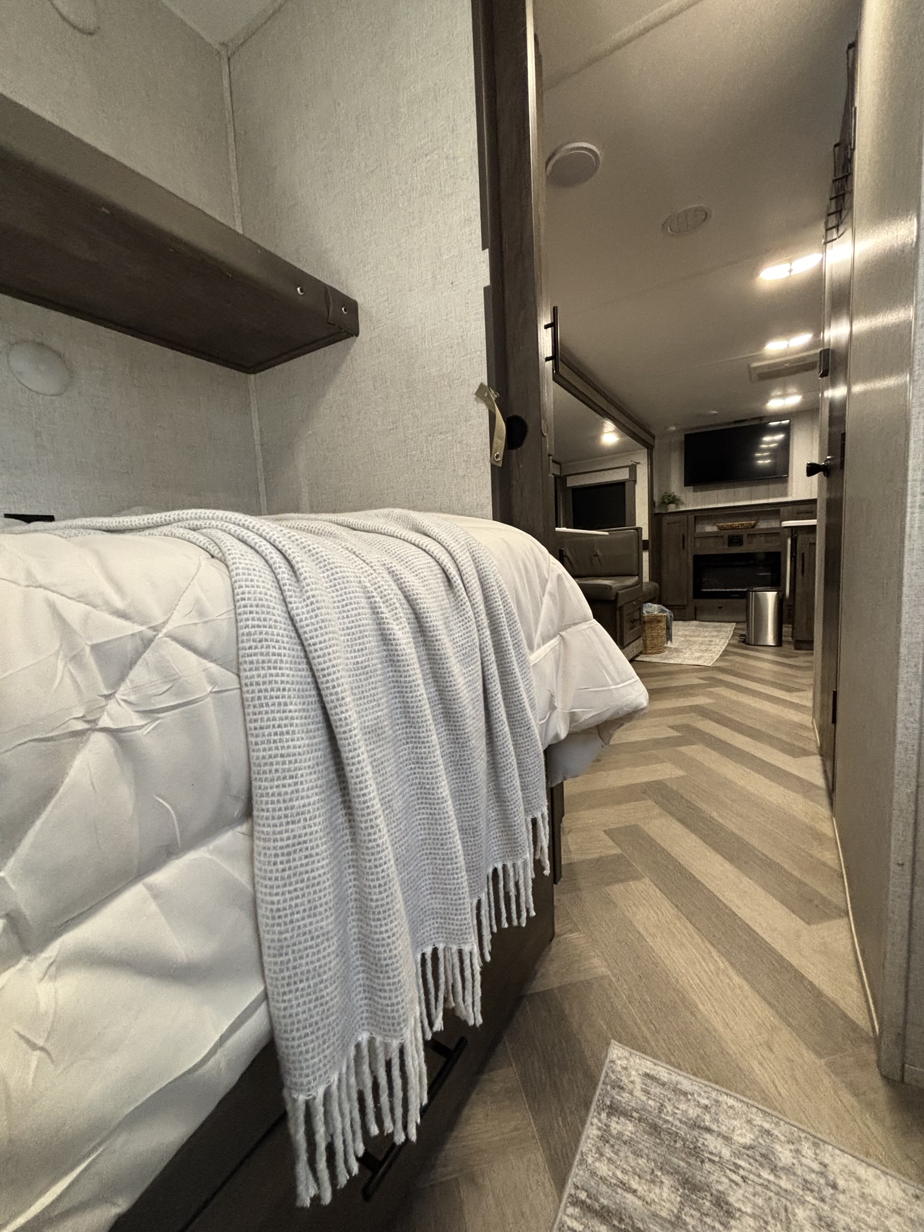 Experience comfort in this modern RV rental! View of a cozy bunk bed area leading to a living space with a TV and fireplace.. Forest River Wildwood 2020
