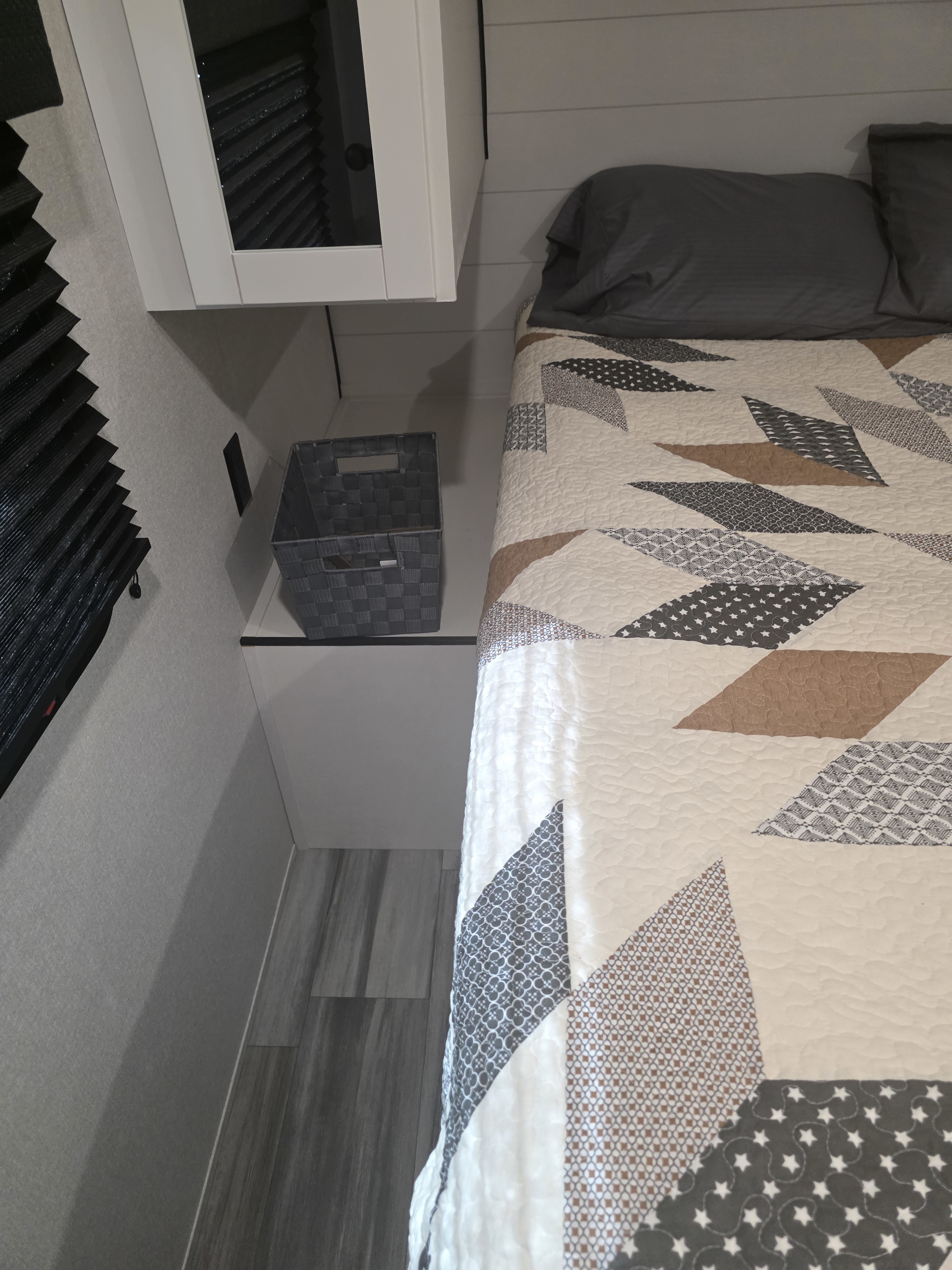 Cozy RV rental bedroom with patterned quilt, grey pillows, overhead cabinet, and a handy woven storage basket.. JAYCO JAY FLIGHT SLX 2026