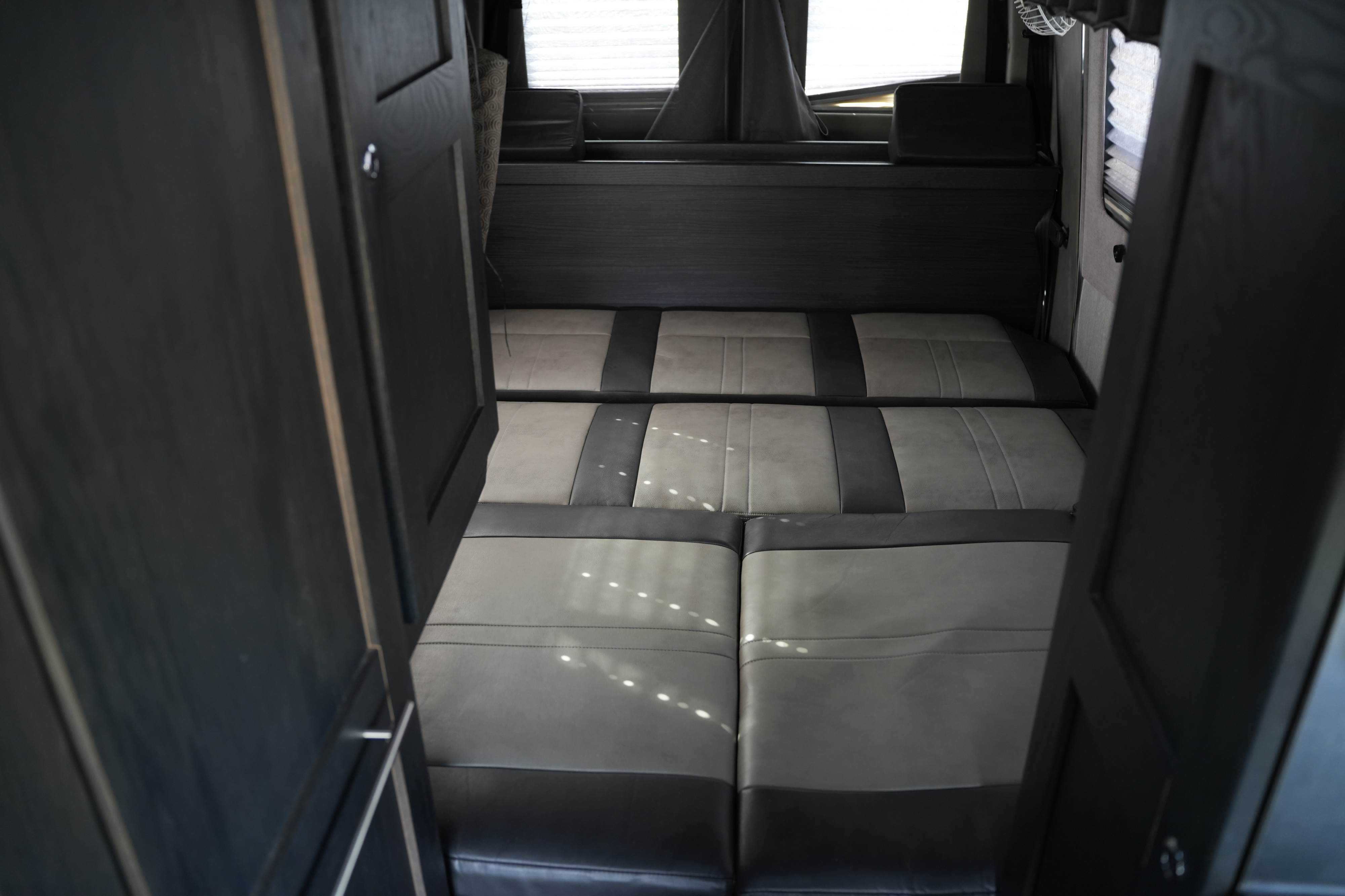 RV rental: Interior with open dark wood doors framing a convertible gray & dark cushion seating/bed & back window.. Roadtrek Mercedes Sprinter Adventurous Rs 2018