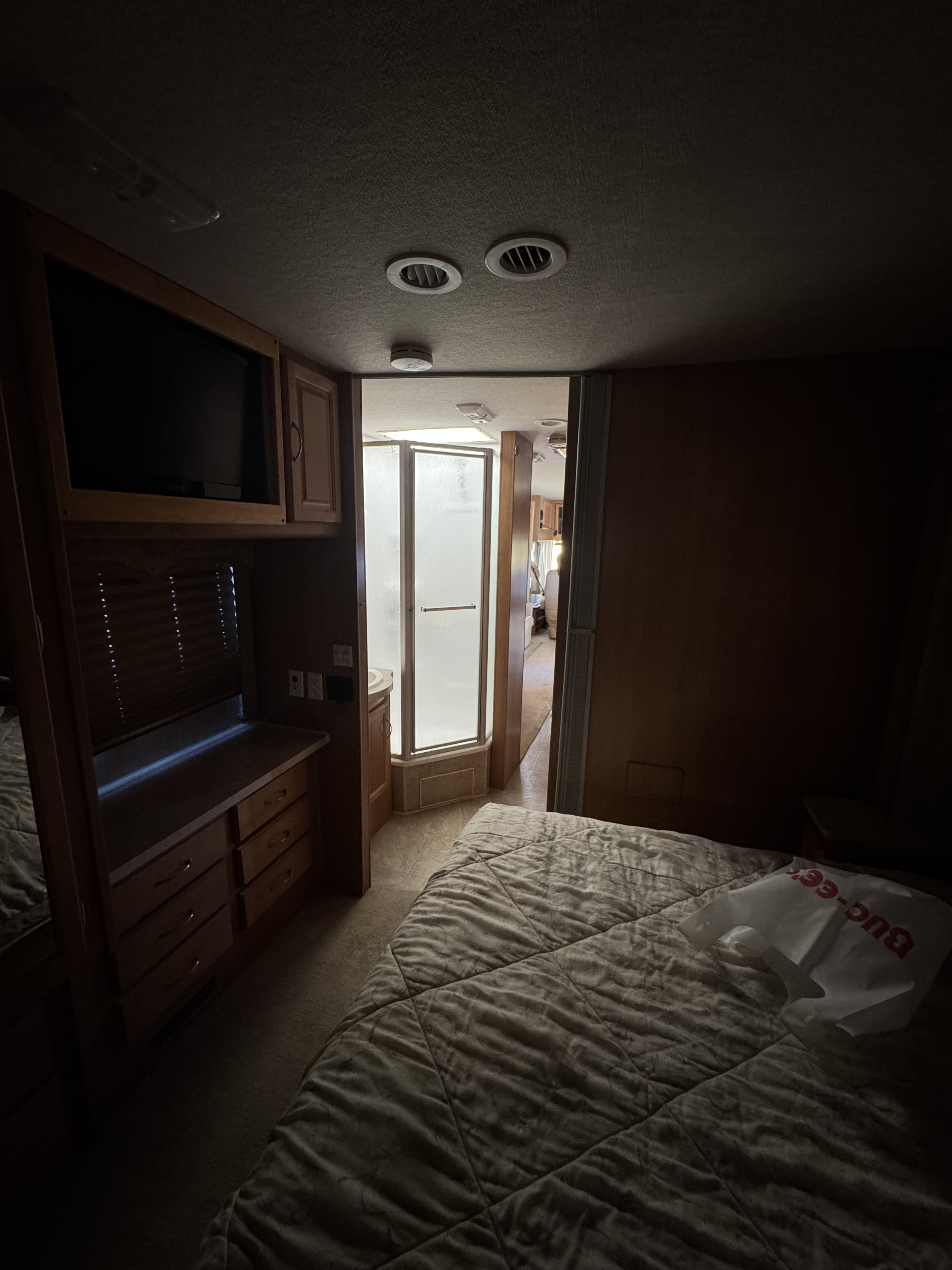 Step inside this cozy RV rental bedroom. Features a comfortable bed, built-in TV, and a connected bathroom with a stand-up shower.. Bounder Bounder Motorhome 2007