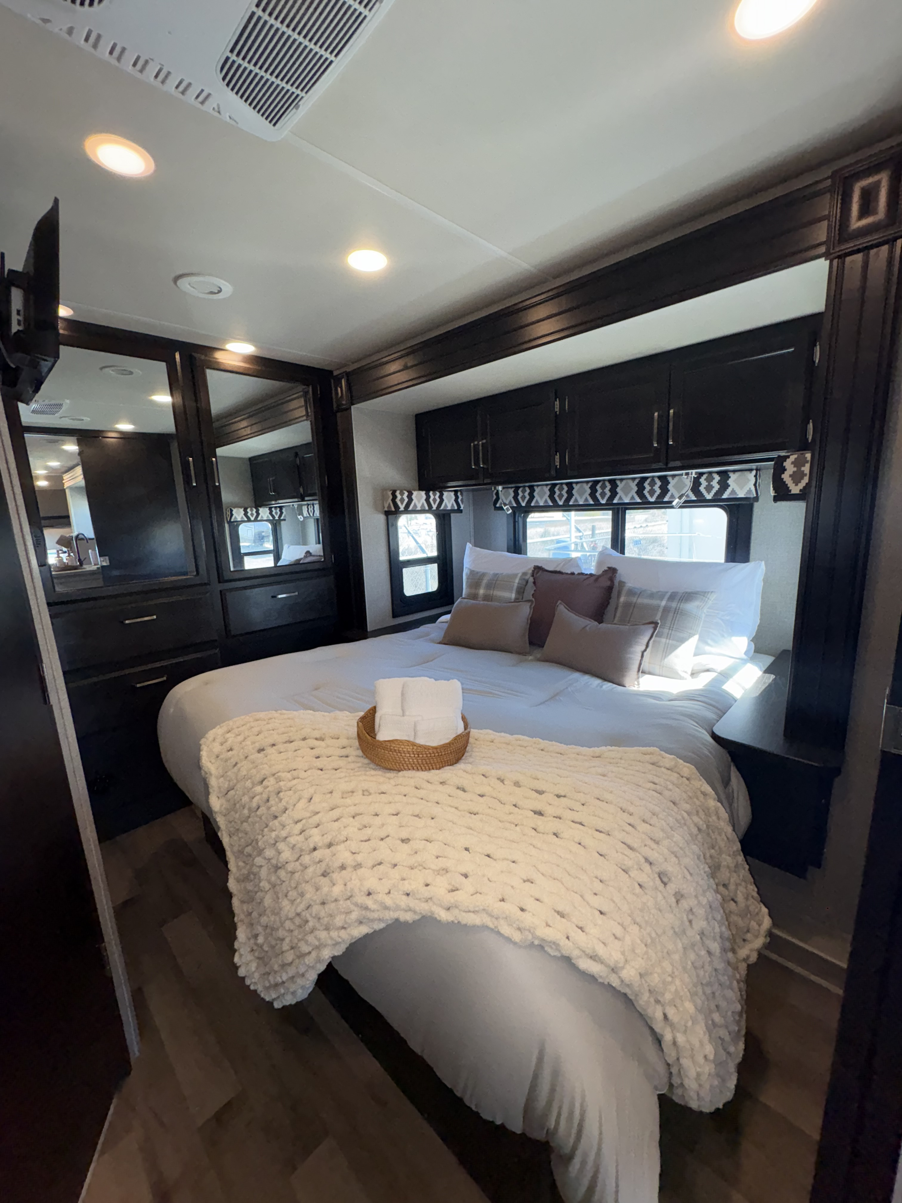 Inviting RV rental bedroom with dark wood storage, a cozy bed, chunky blanket, & mirrored wardrobe for a comfortable stay.. Jayco Greyhawk 2020