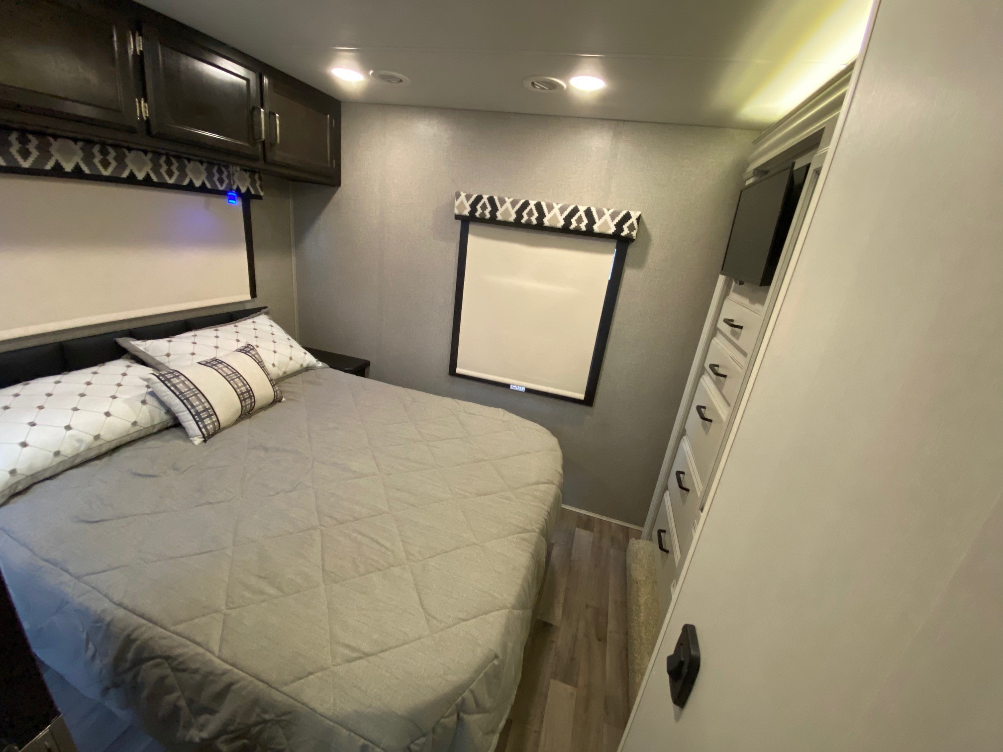 RV rental bedroom with a comfortable bed, overhead cabinets, window, and TV. Ready for your adventure.. Jayco Greyhawk 2022