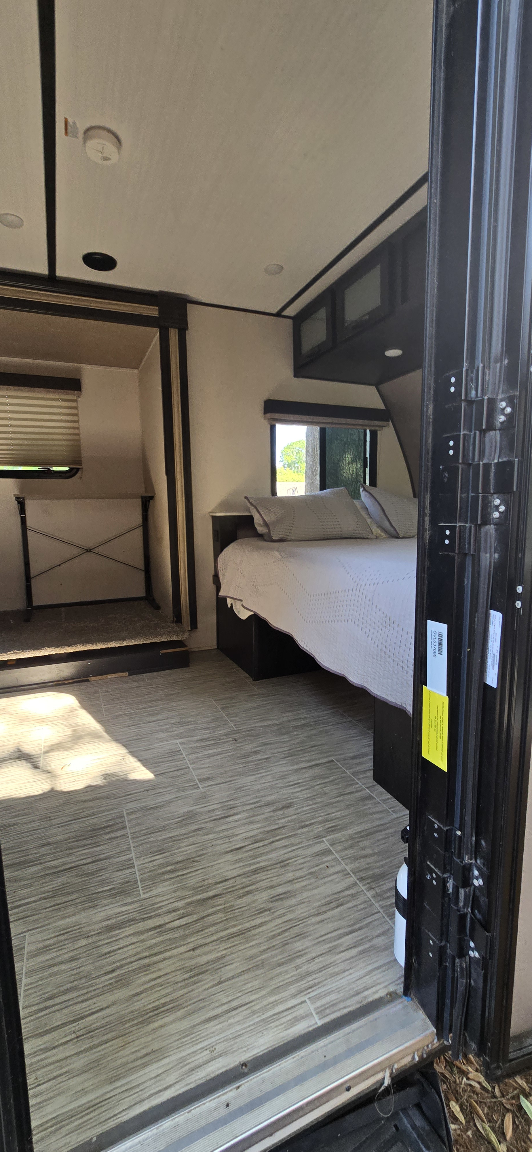 This RV rental interior features a bedroom with a bed, windows, and cabinets, plus a bunk area and light-tiled floor.. Forest River Surveyor Legend 2020